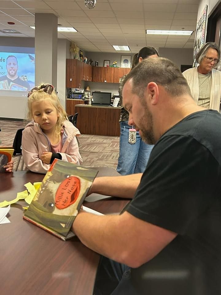 AB Wade signs book for child at a school visit
