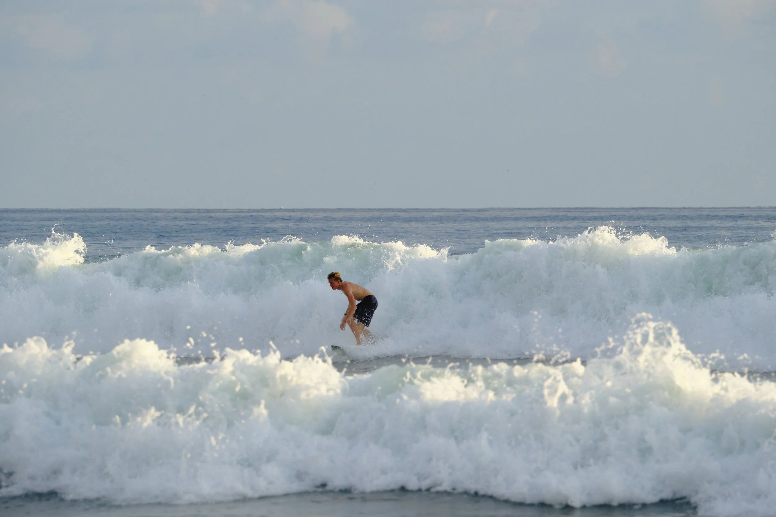 A man surfing on a wave in the ocean near the shoreline.