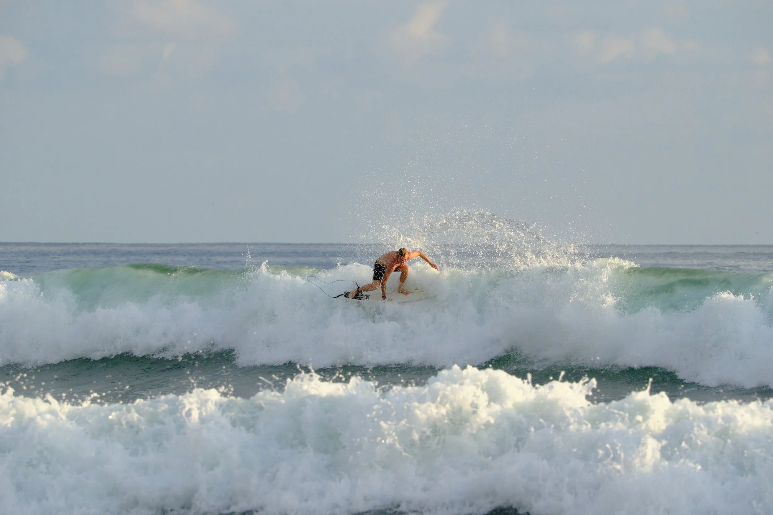 A person surfing on a wave in the ocean during daytime.