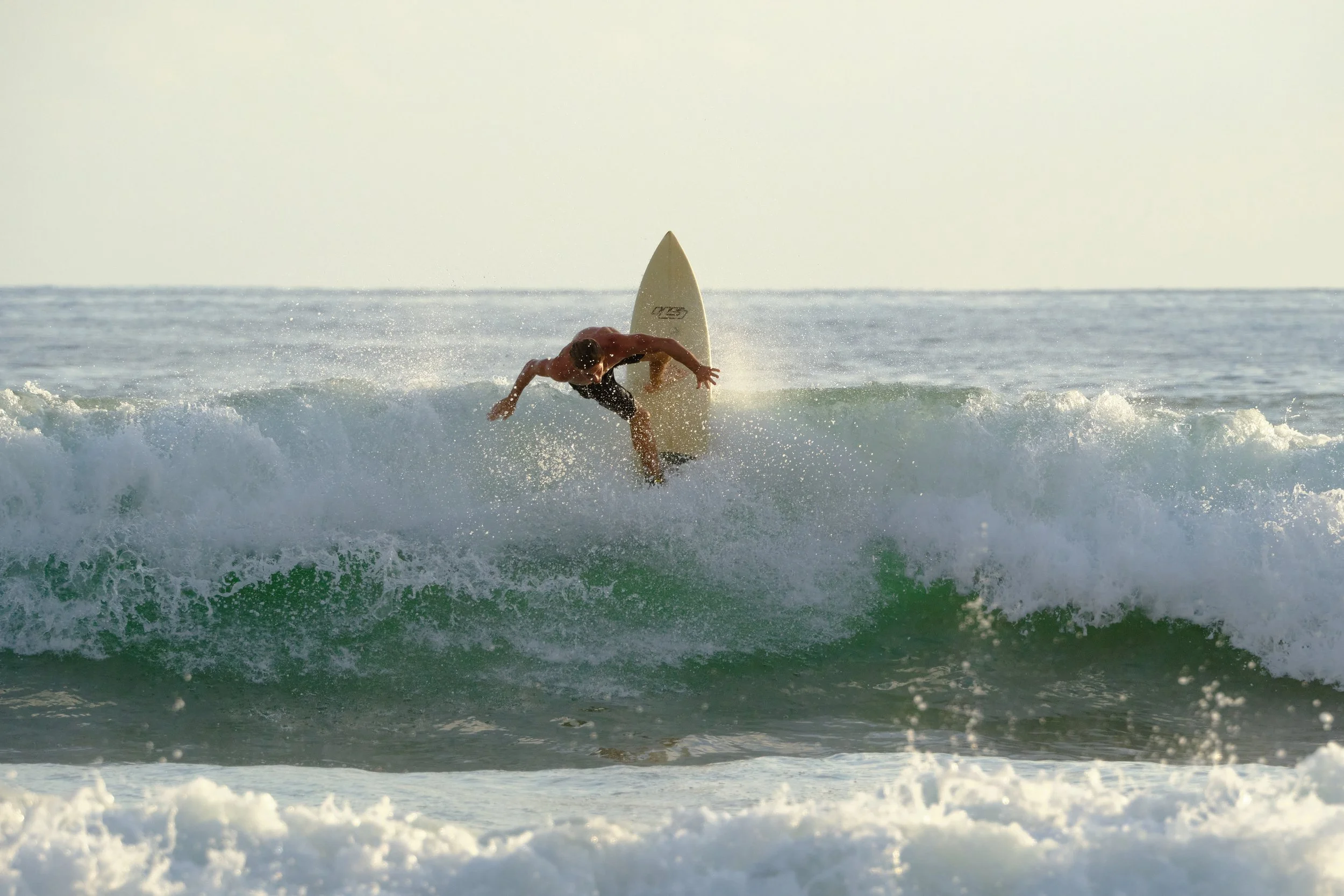 A male surfer riding a wave in the ocean.
