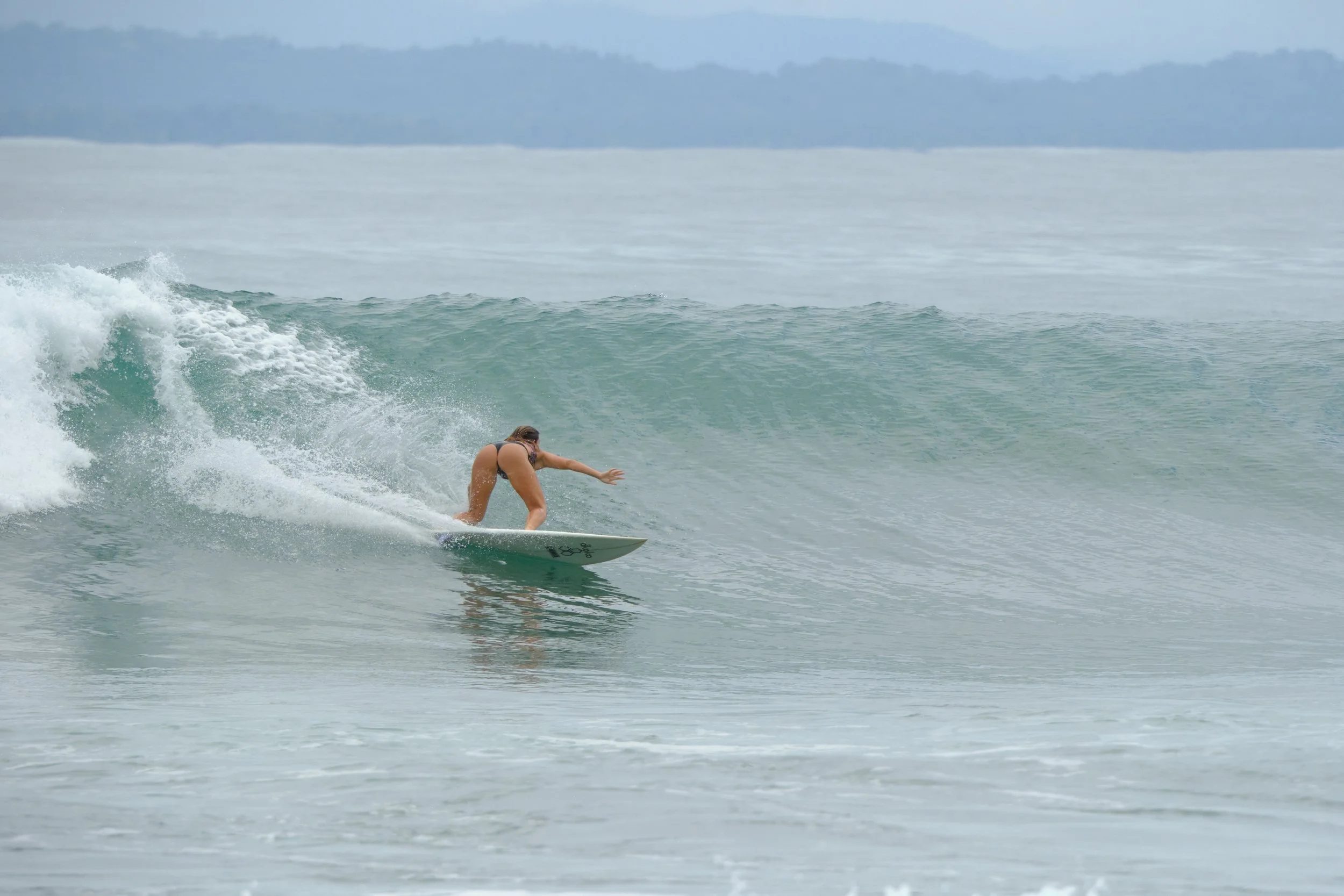 A woman in a bikini surfing on a wave in the ocean.
