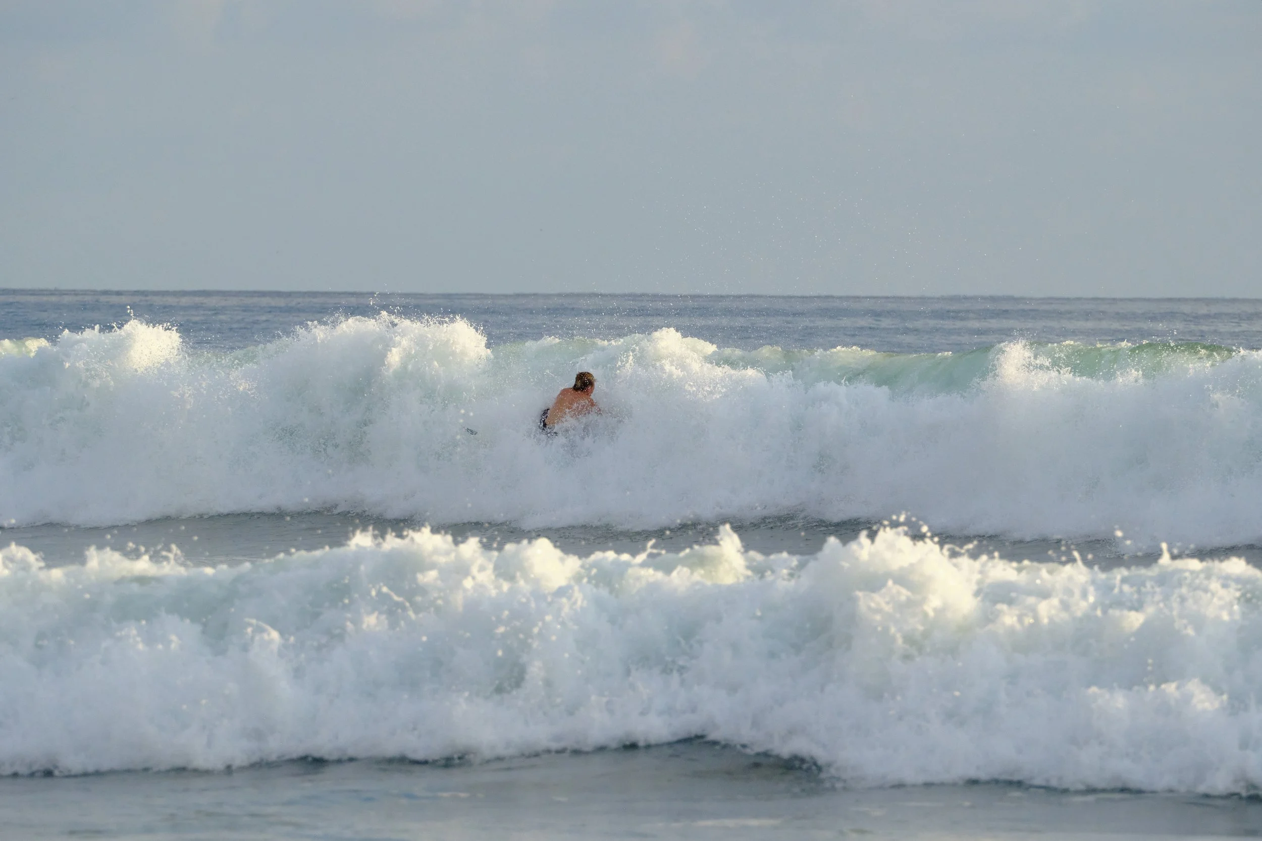 A person surfing in the ocean, riding a wave.