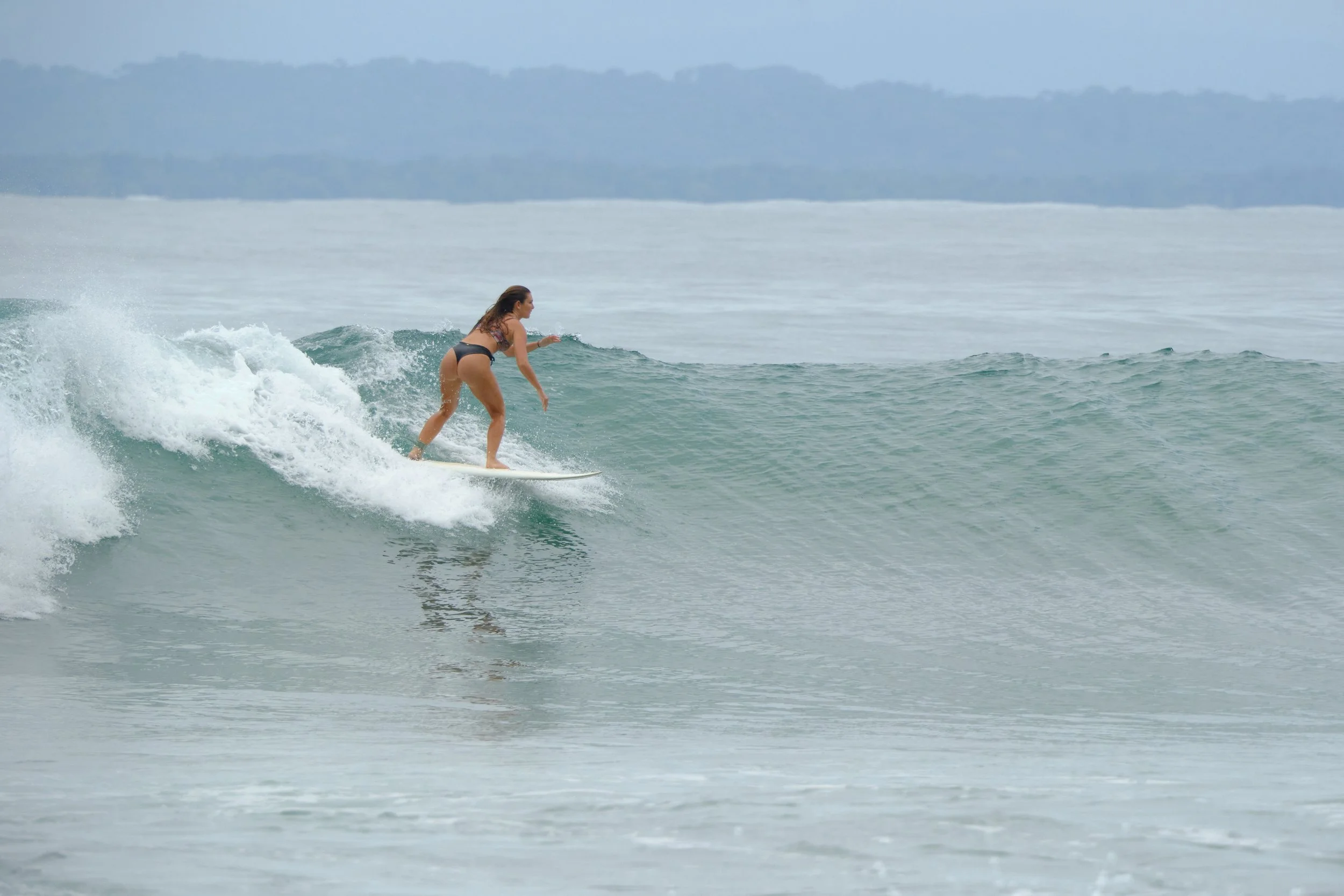 A woman in a bikini surfing on a small wave in the ocean during daytime.