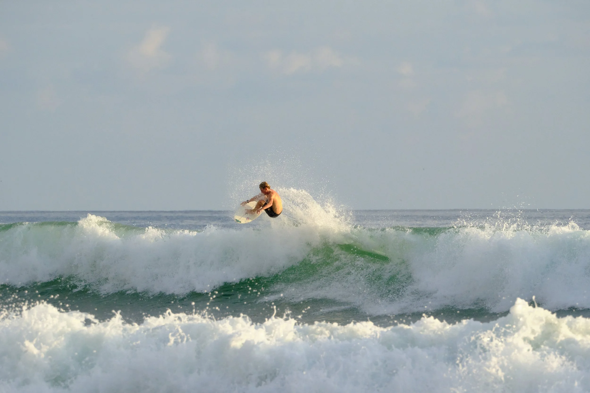 A shirtless man riding a wave on a surfboard in the ocean.