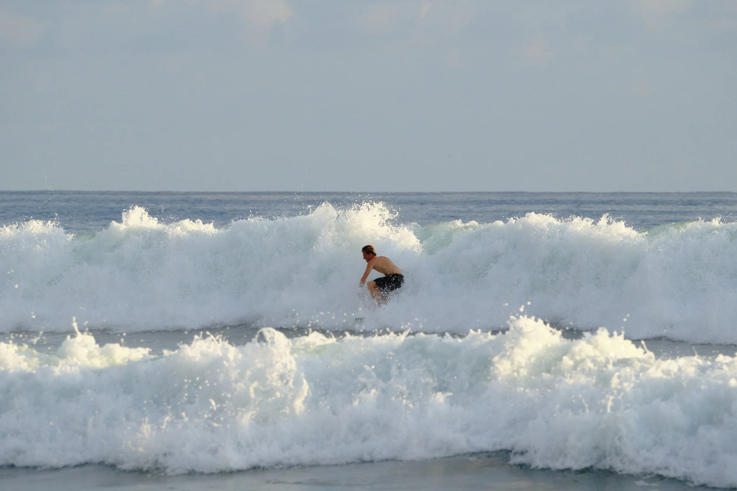 A person surfing on a wave in the ocean during daytime.
