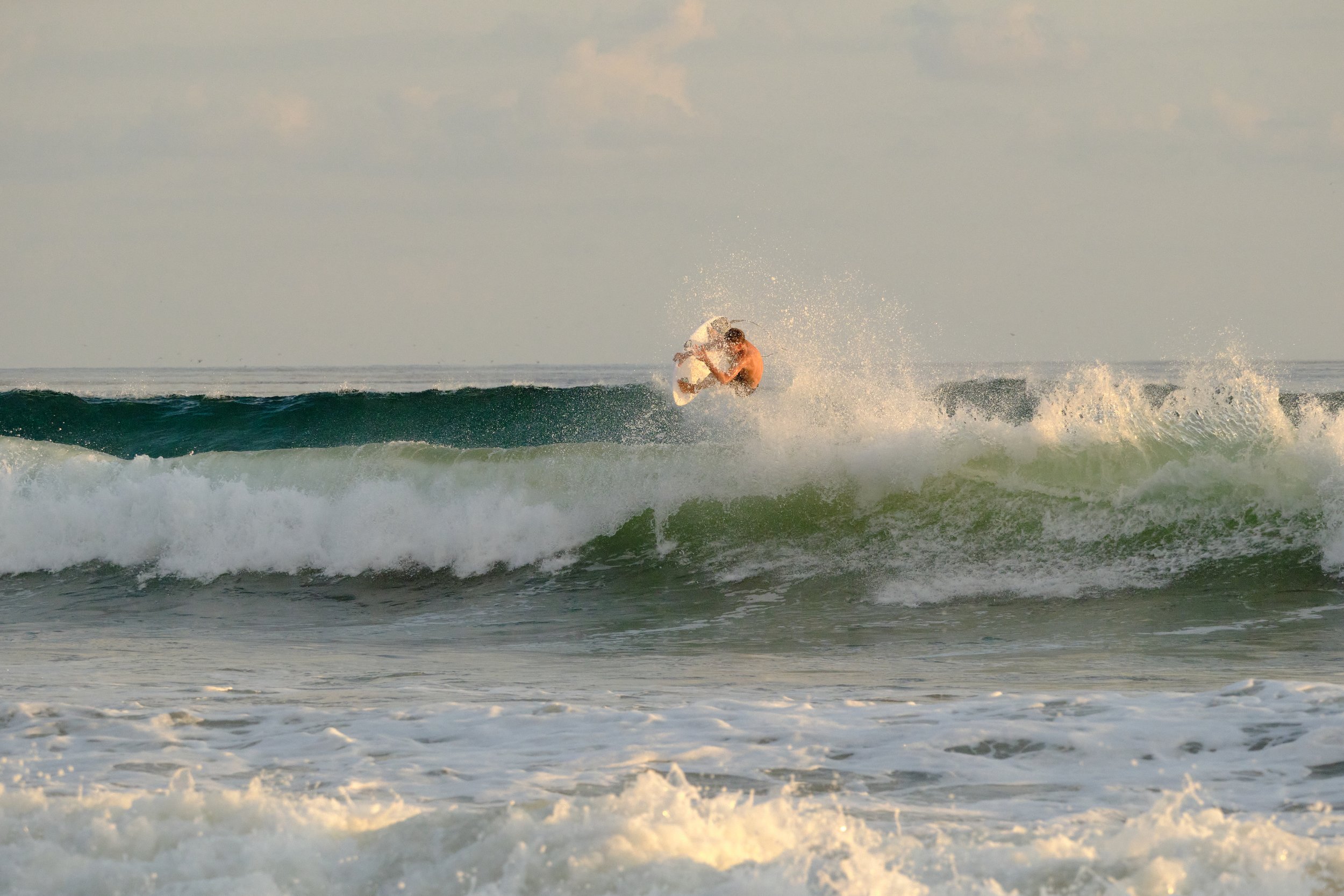 A person surfing on a wave in the ocean during daylight