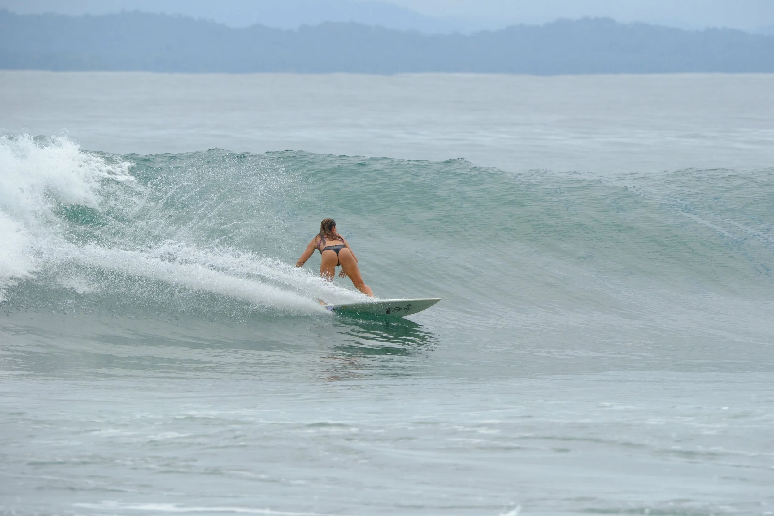 A woman in a bikini surfing on a wave in the ocean.