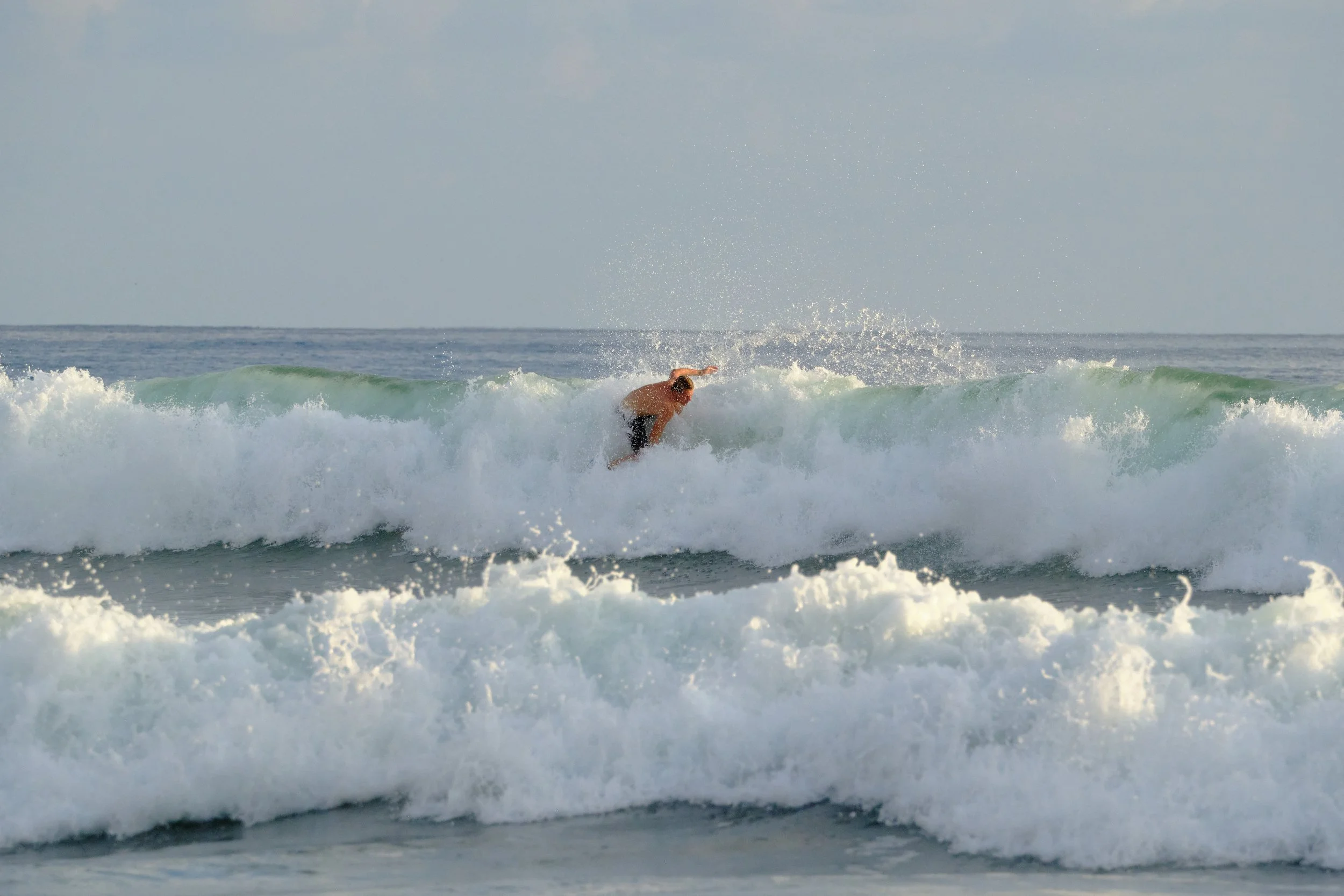 A person surfing on a wave in the ocean during daylight.