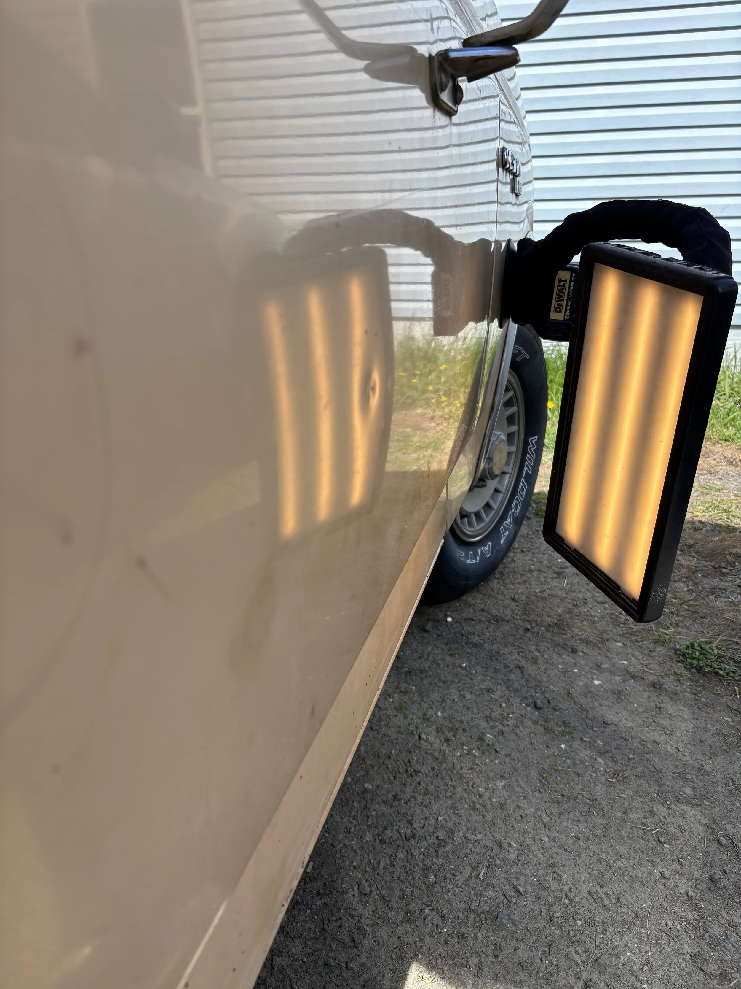 Dent repair light reflecting on a vehicle door panel, highlighting imperfections.