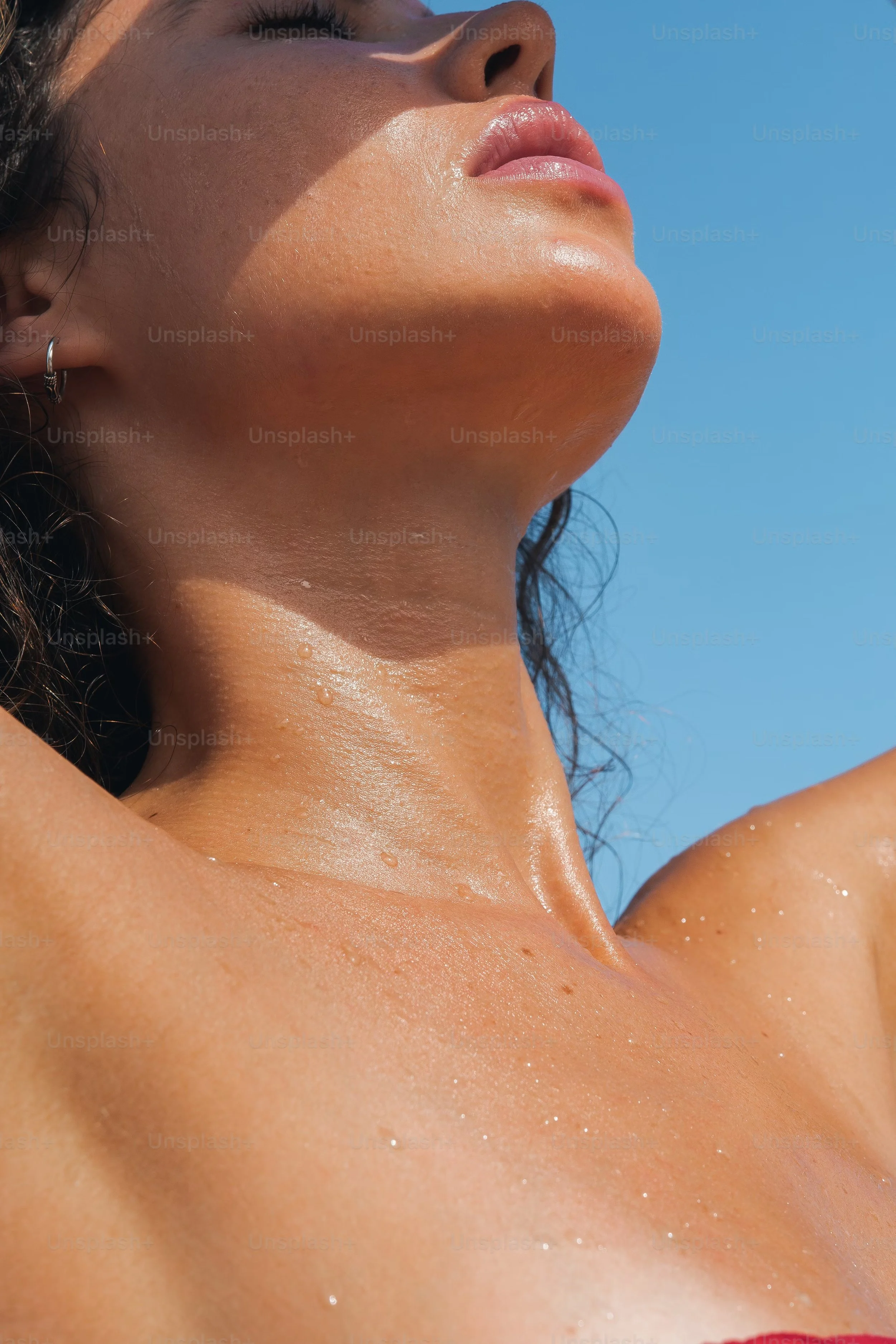 Close-up of woman's glistening skin and neck under sunlight