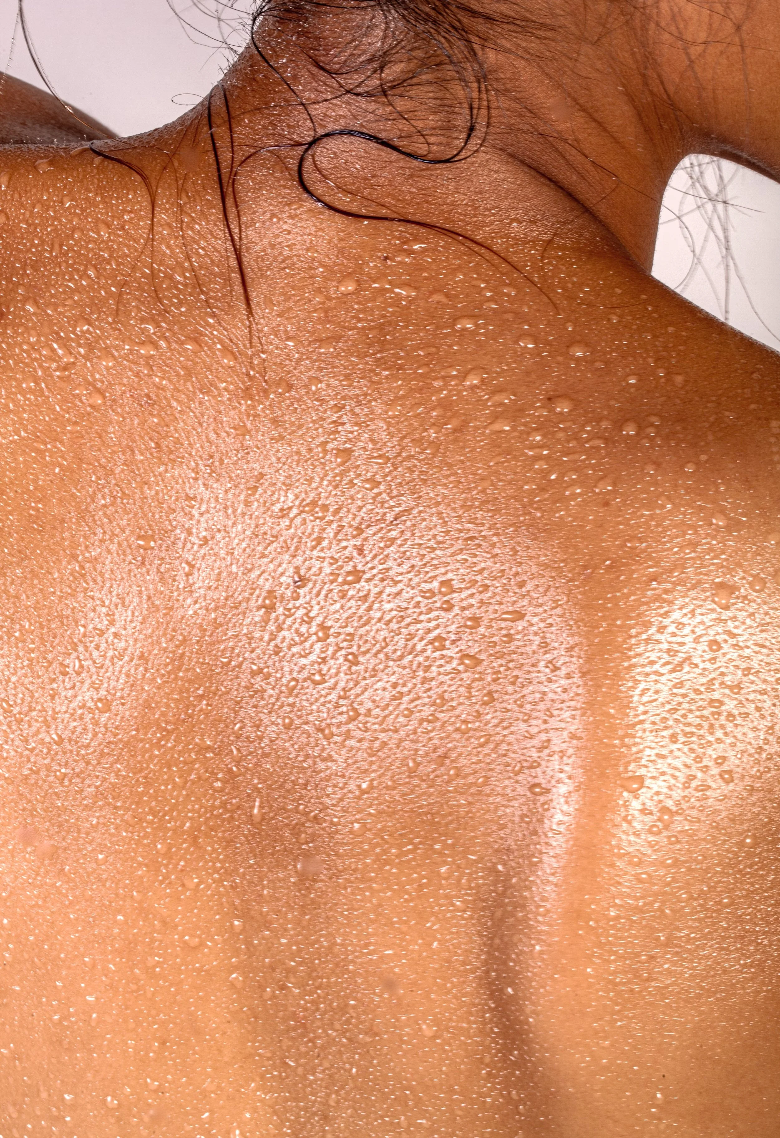 Close-up of a person's wet, sweaty back with hair strands.