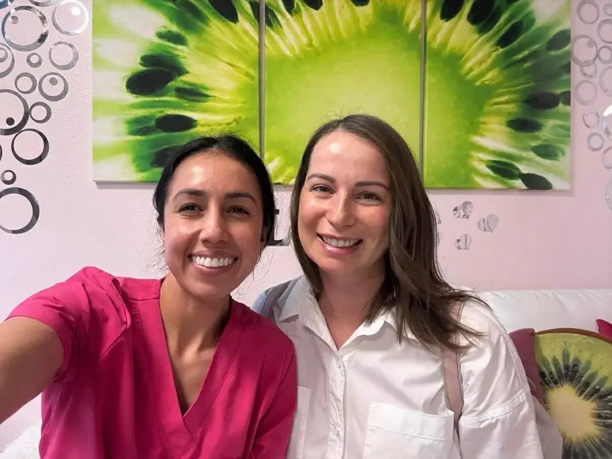 A woman with glowing skin and her esthetician smiling side by side