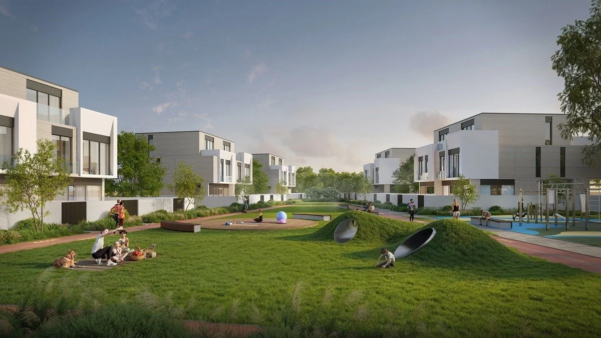 Modern residential complex with a shared outdoor recreational area featuring children playing, adults sitting on the grass, trees, and playground equipment.