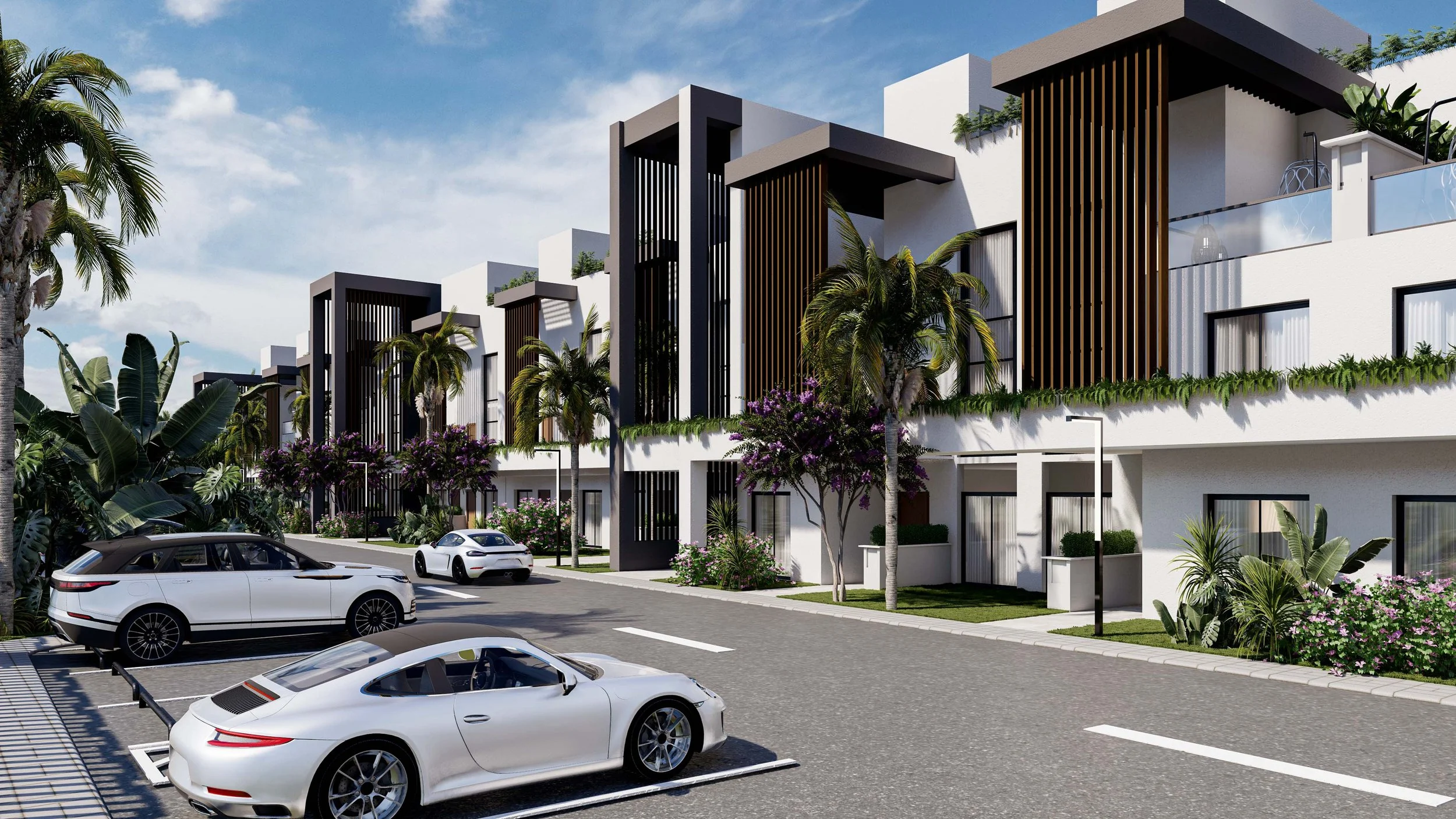 Modern residential apartment complex with white buildings, black vertical wooden accents, palm trees, flowering plants, parked white cars, and a clear blue sky.
