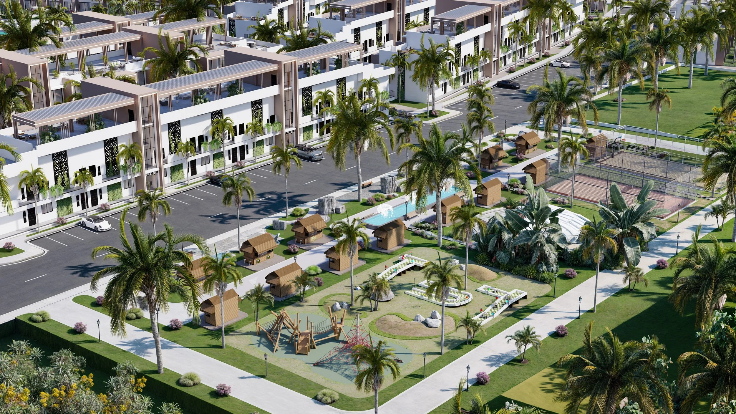 Aerial view of a modern residential complex surrounded by palm trees, featuring a parking lot, small houses, a playground, tennis courts, and landscaped gardens.