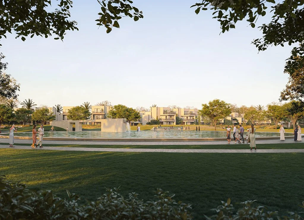 A park with a fountain, surrounded by trees and modern residential buildings, with people walking and sitting.