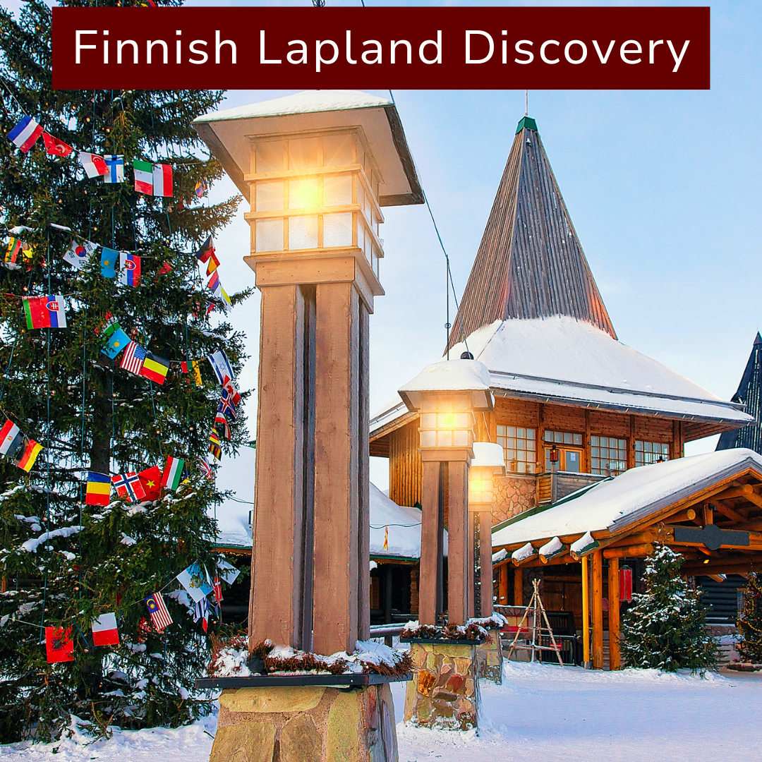 A snow-covered Finnish building with a tall wooden spire, decorated with a large Christmas tree and string of international flags, labeled 'Finnish Lapland Discovery'.