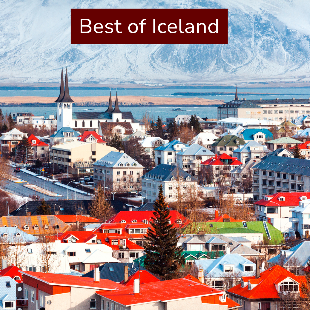 Scenic view of a town in Iceland with colorful houses, a church with tall spires, mountains, and a body of water in the background.