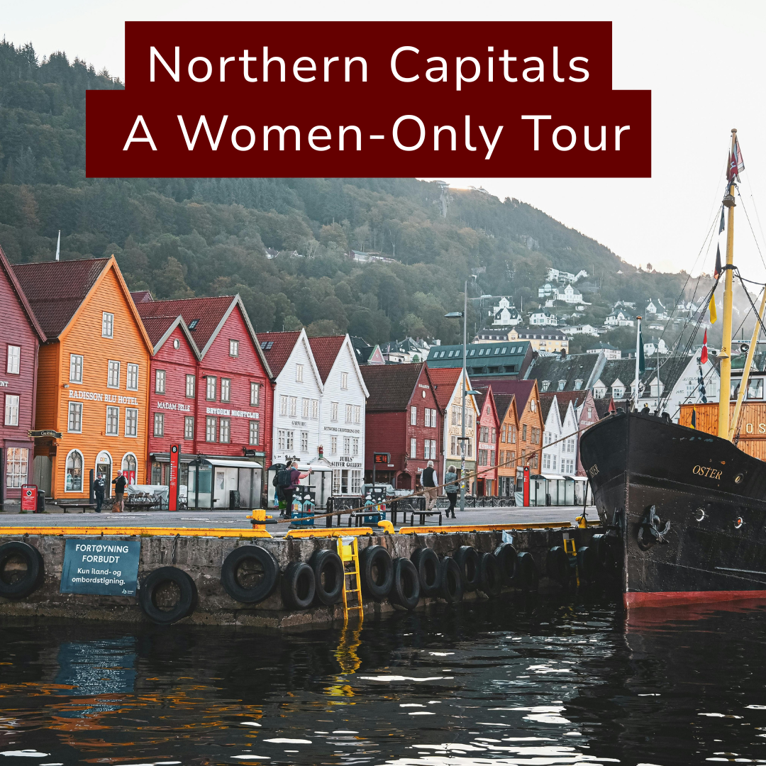 Colorful wooden houses along a harbor with a docked boat and hills in the background, promoting a women-only tour of Norwegian capitals.