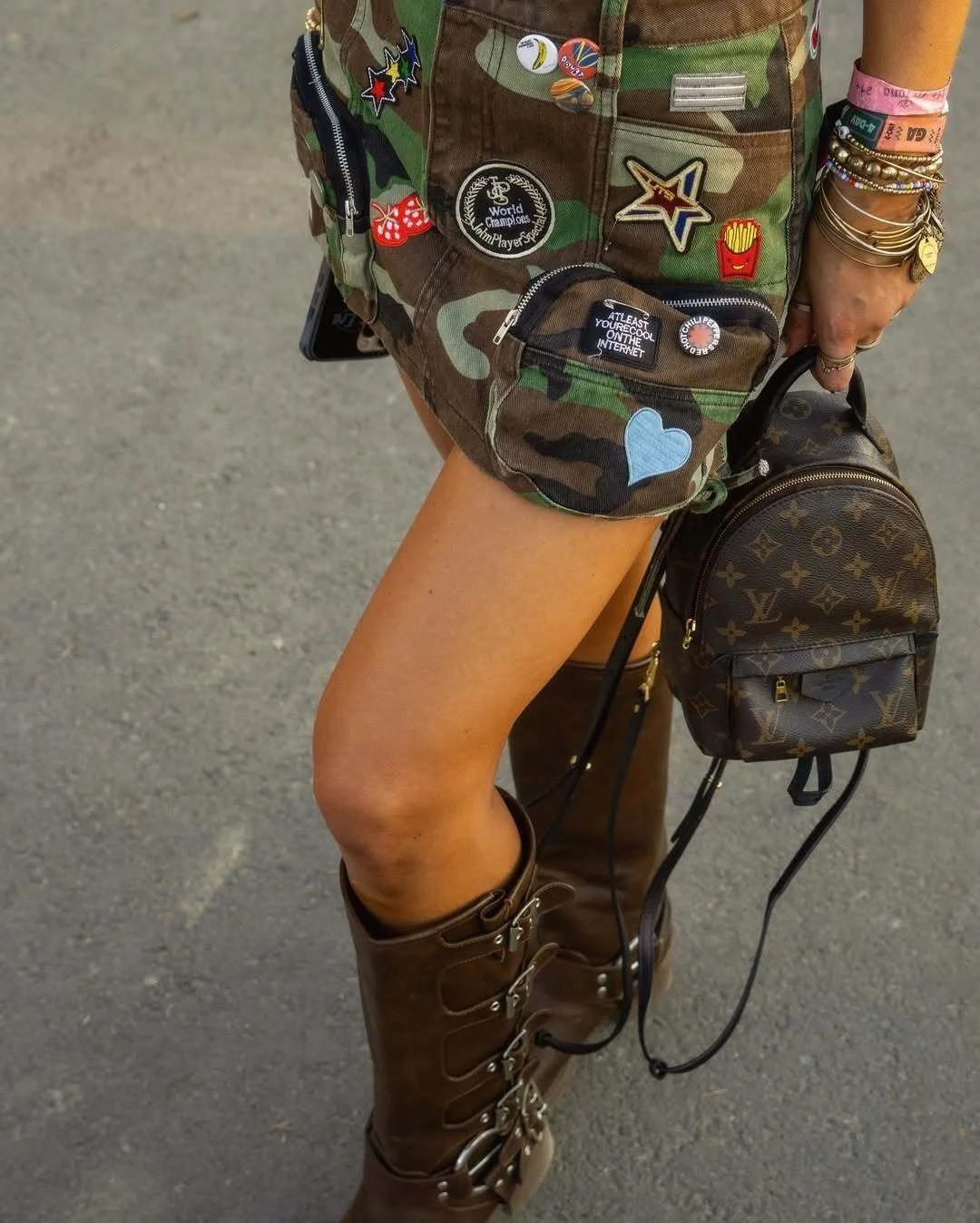 Close-up of a DIY camo mini skirt covered in iron-on patches styled for a festival outfit.