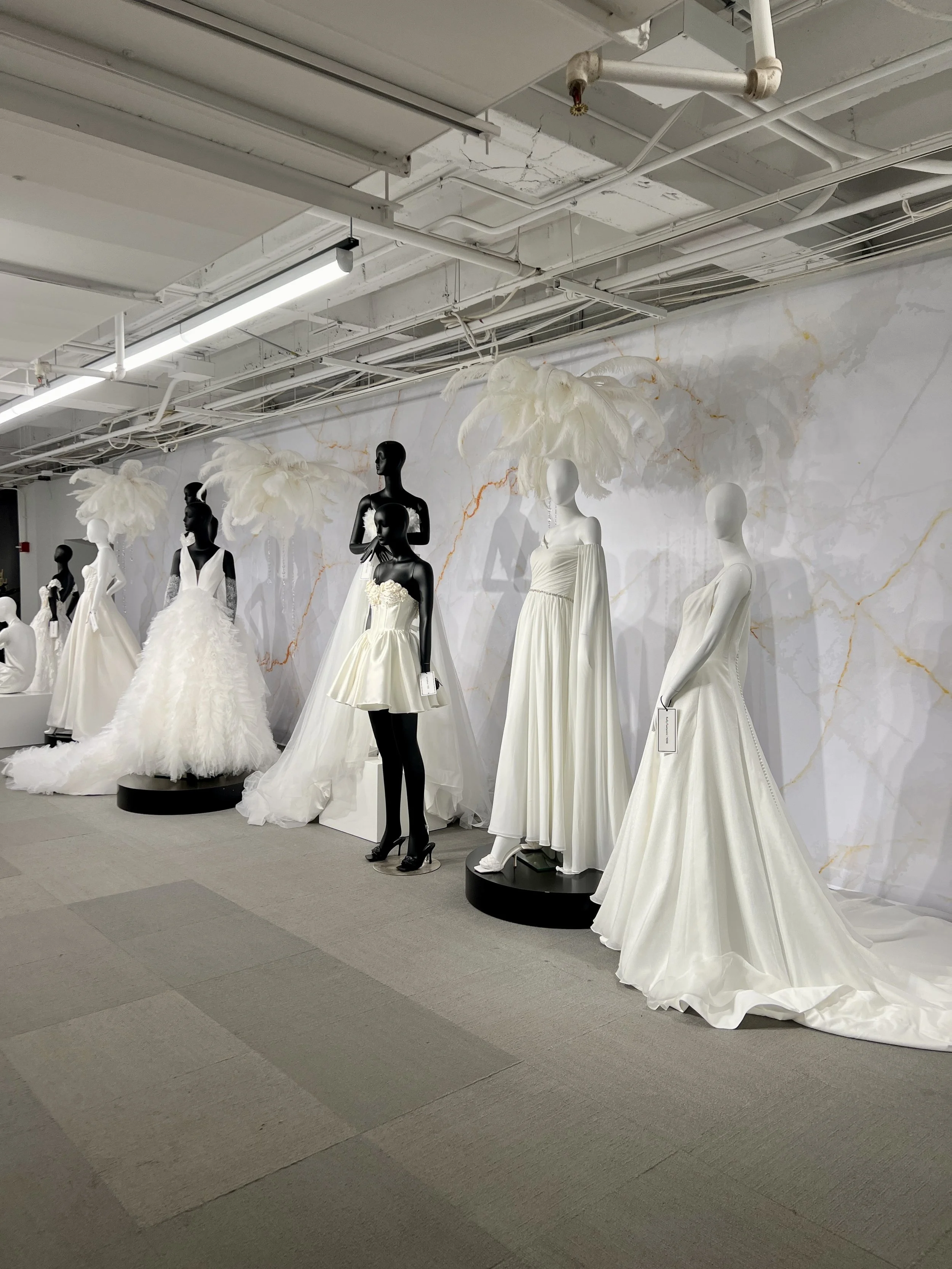 Bridal showroom display with white wedding gowns on mannequins inside Chicago Bridal Market exhibition space.