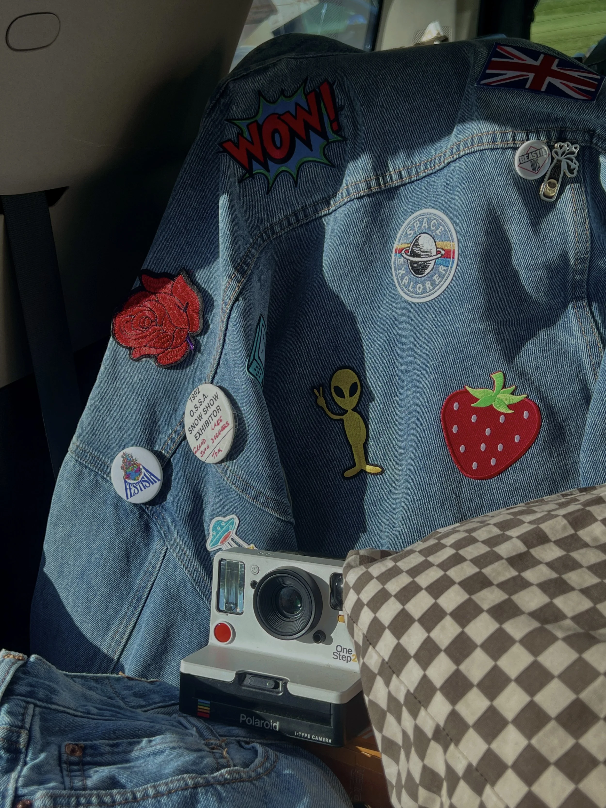 Close-up of a DIY denim jacket covered in iron-on patches styled for a festival outfit.