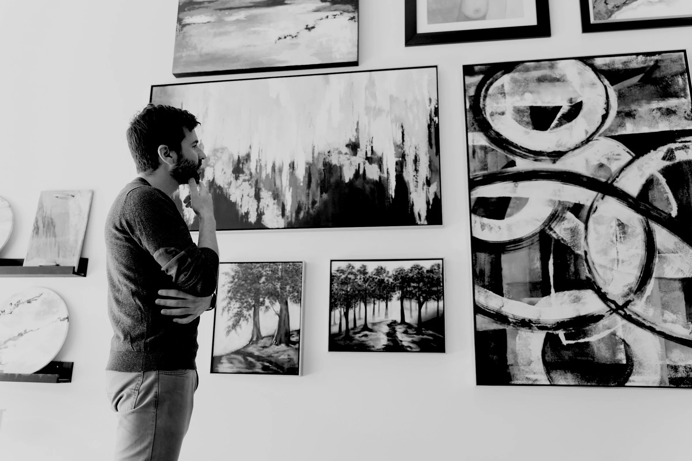black and white photo of a man looking at wall of art