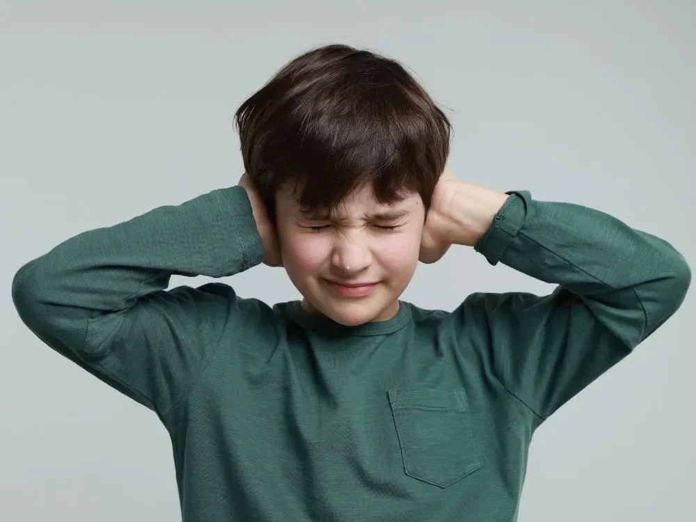 A child covering their ears in a noisy environment