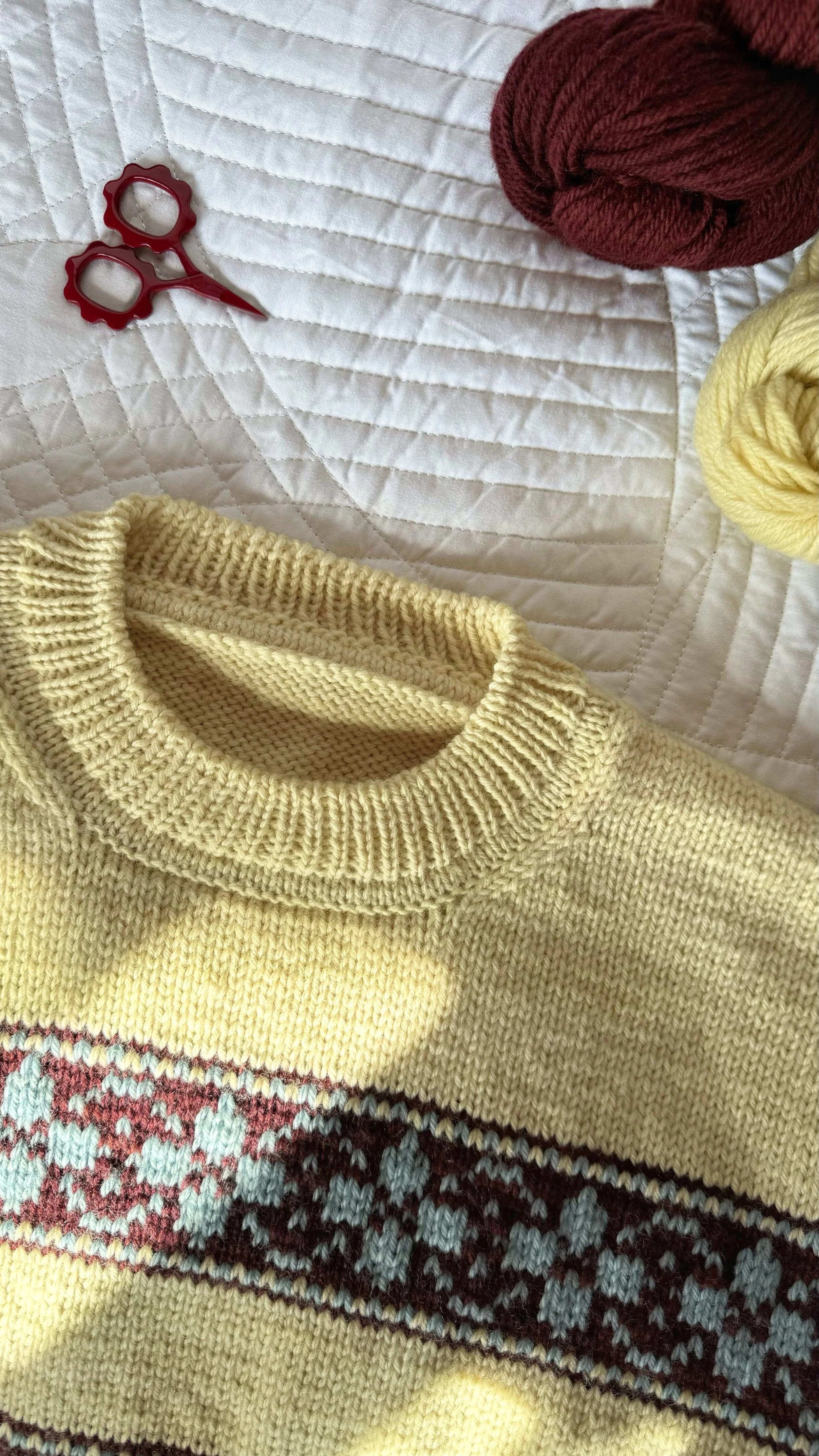hilda sweater in yellow base with colorwork stripes in burgundy, and flowers in light blue
