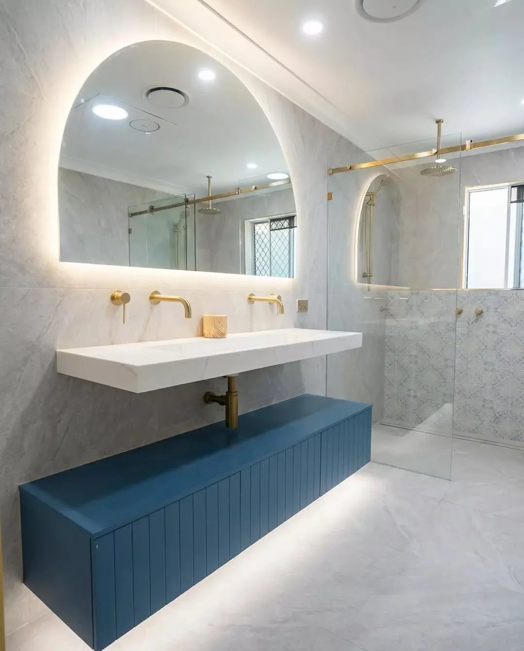 We love when clients aren&rsquo;t afraid to add a bit of personality. The deep blue vanity becomes the feature of the room, while the brass fixtures and soft lighting keep the whole space feeling balanced and calm. A bathroom that definitely stands o