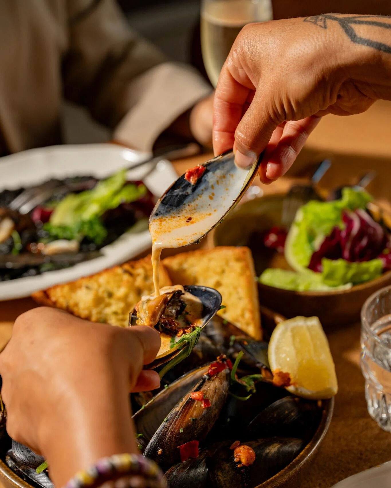 Steamed mussels with fermented chilli, coconut milk, warrigal, macadamia chilli crunch and confit garlic bread 🐚