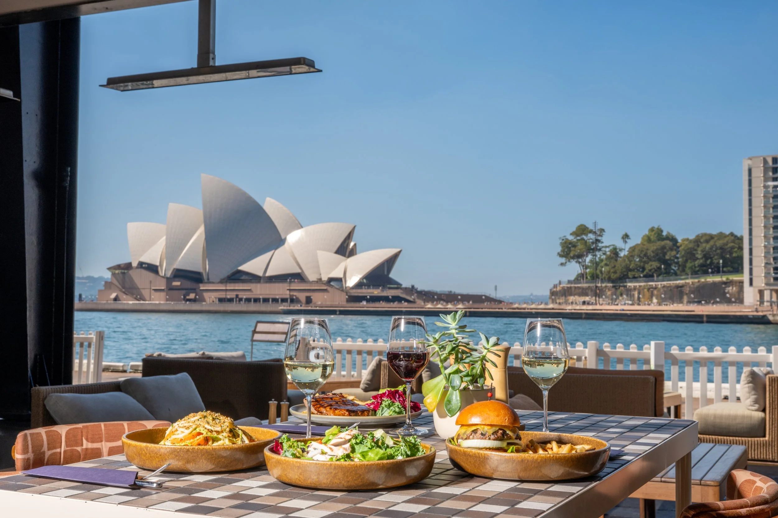 Lunch classics served on an outdoor table at Cruise Bar + Restaurant with a scenic backdrop of the Sydney Opera House.