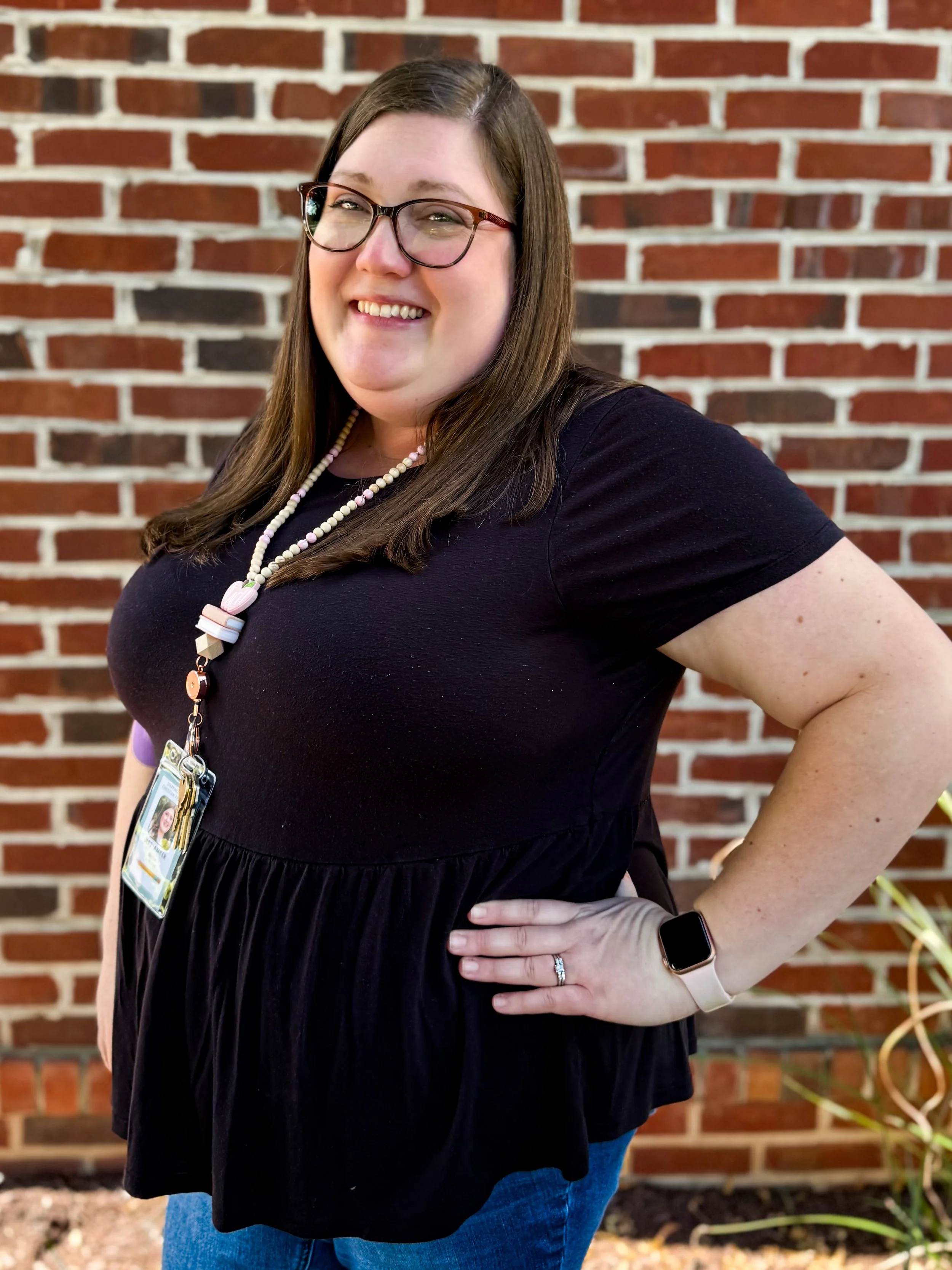 Picture of a young woman in a black shirt with glasses and brown straight hair