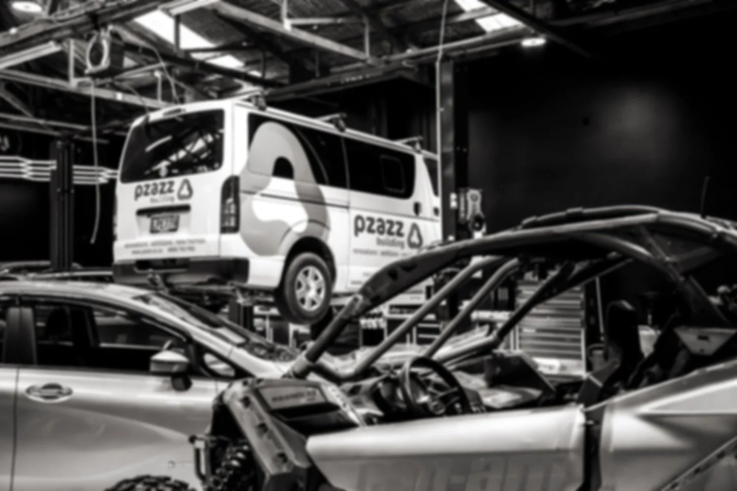 White van on a hydraulic lift in an auto repair shop, with logos and text for 'PERSONNEL TOUCH' and contact number, and a technician working nearby.