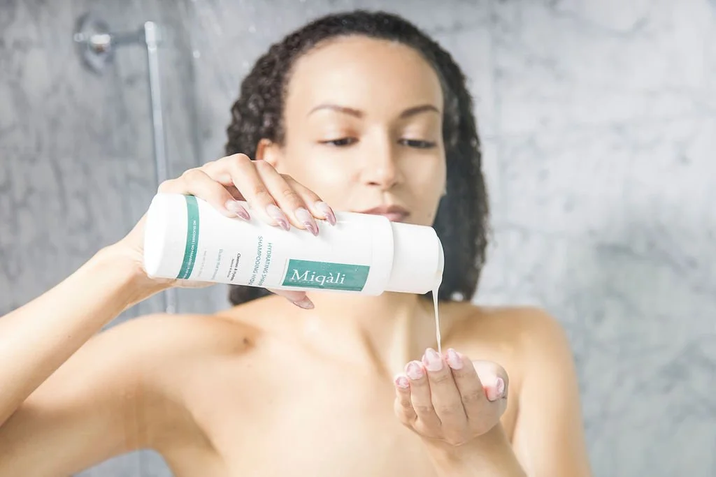 Woman pouring shampoo into her hand while in the shower.