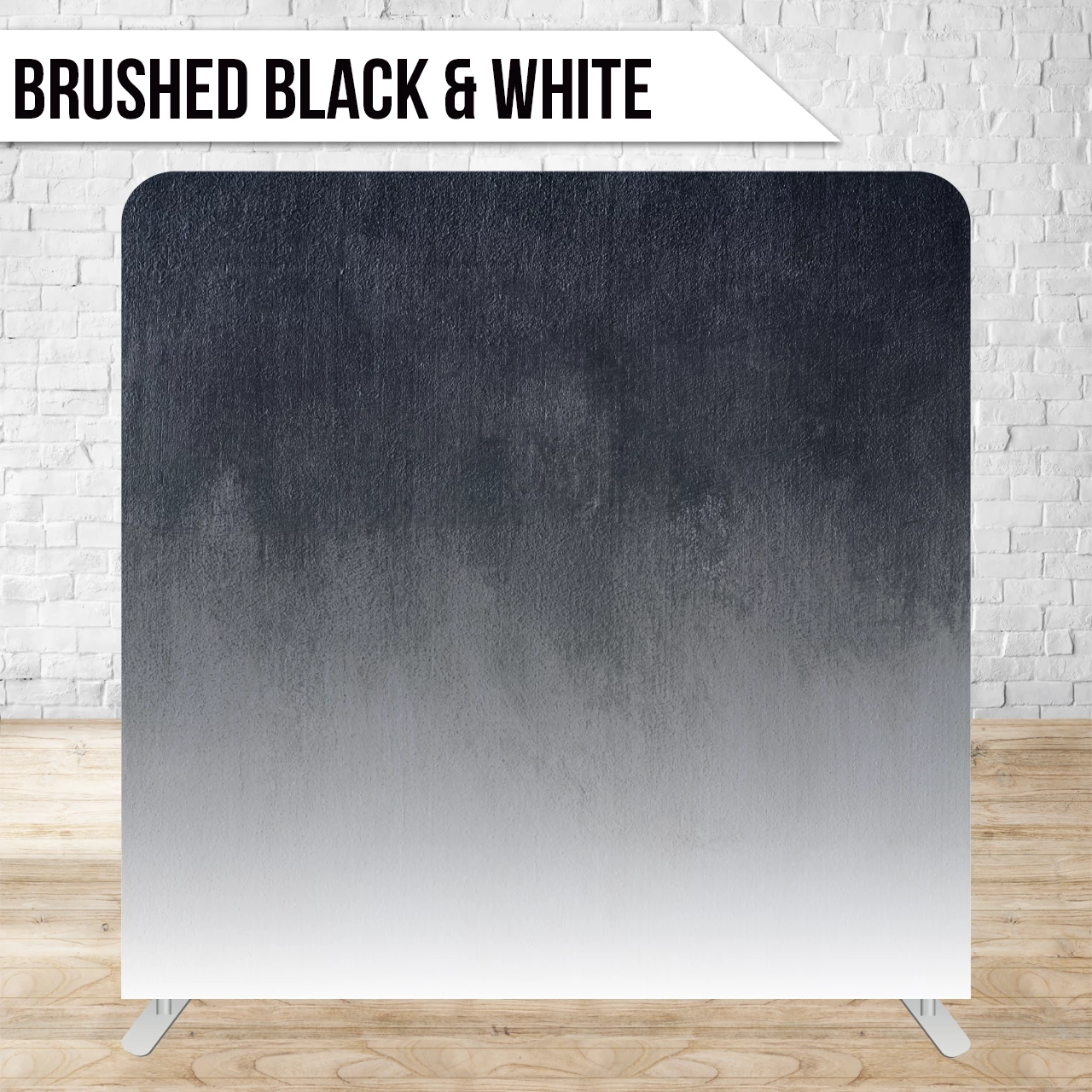 Gradient backdrop with brushed black and white texture on a wooden floor, labeled 'Brushed Black & White'. Brick wall in the background.