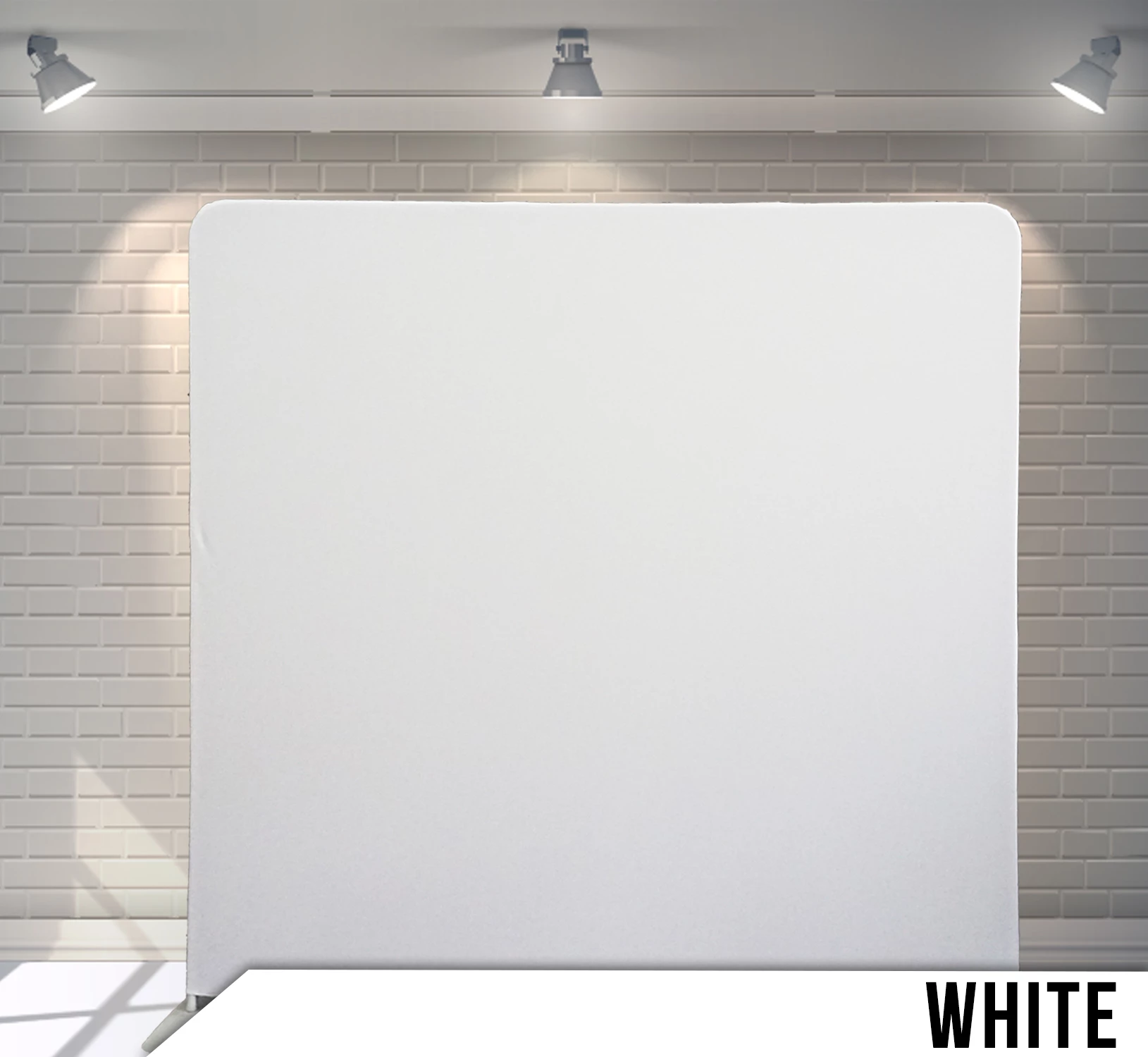 White backdrop in front of a brick wall with spotlighting.