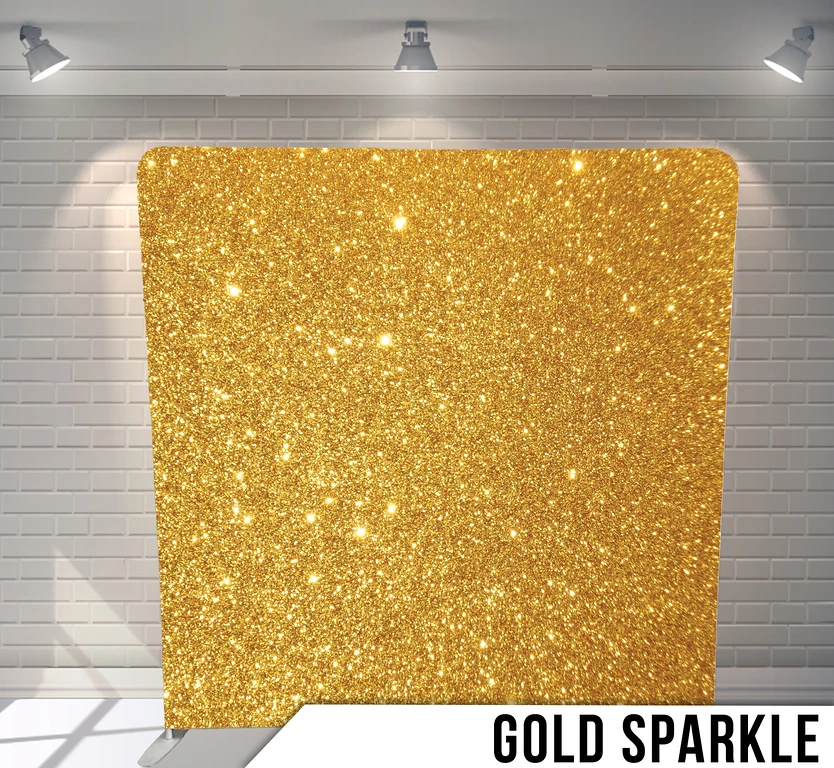 Gold sparkle backdrop against a white brick wall with overhead spotlights.