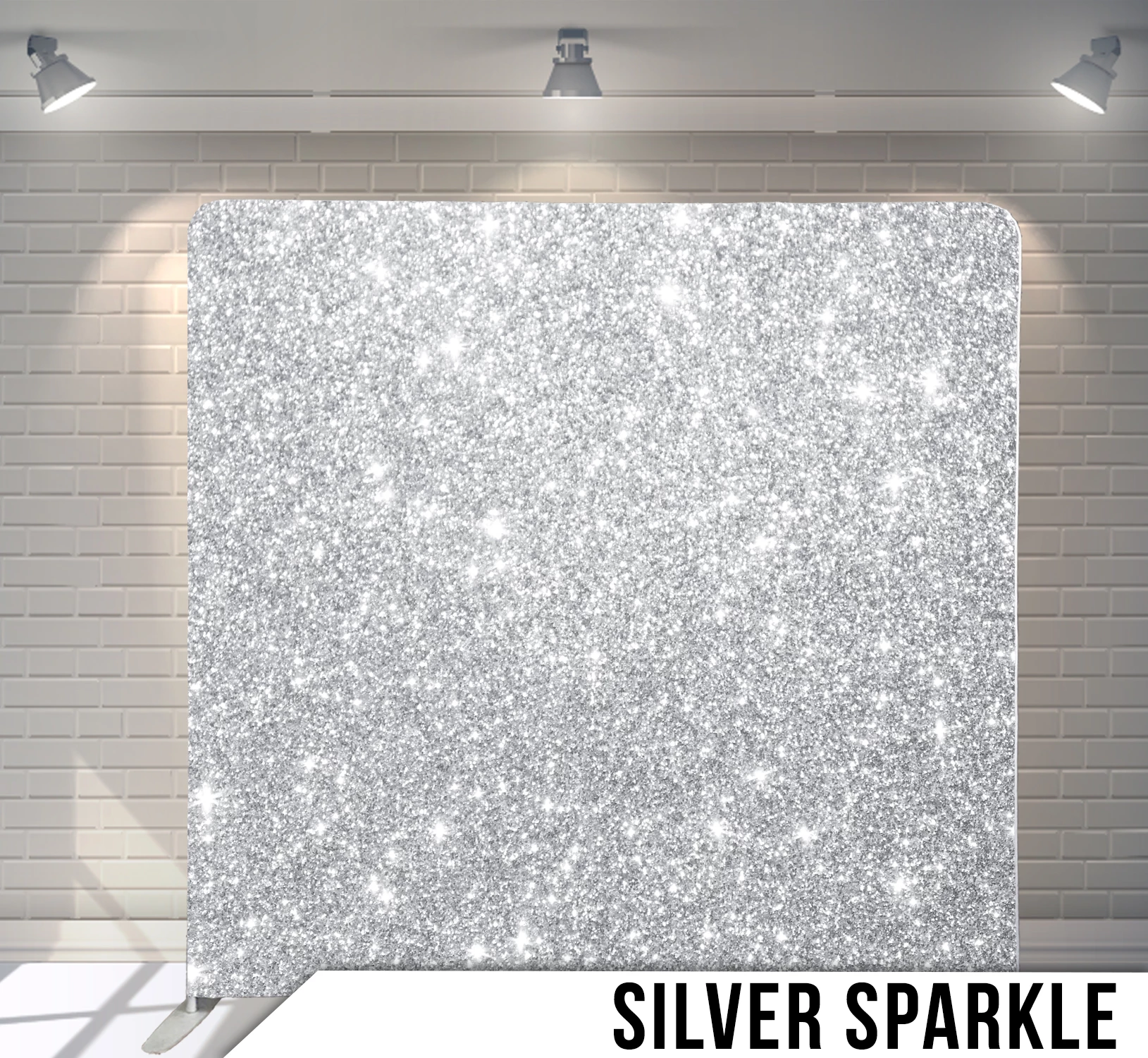 Silver sparkle backdrop against a brick wall under spotlights.