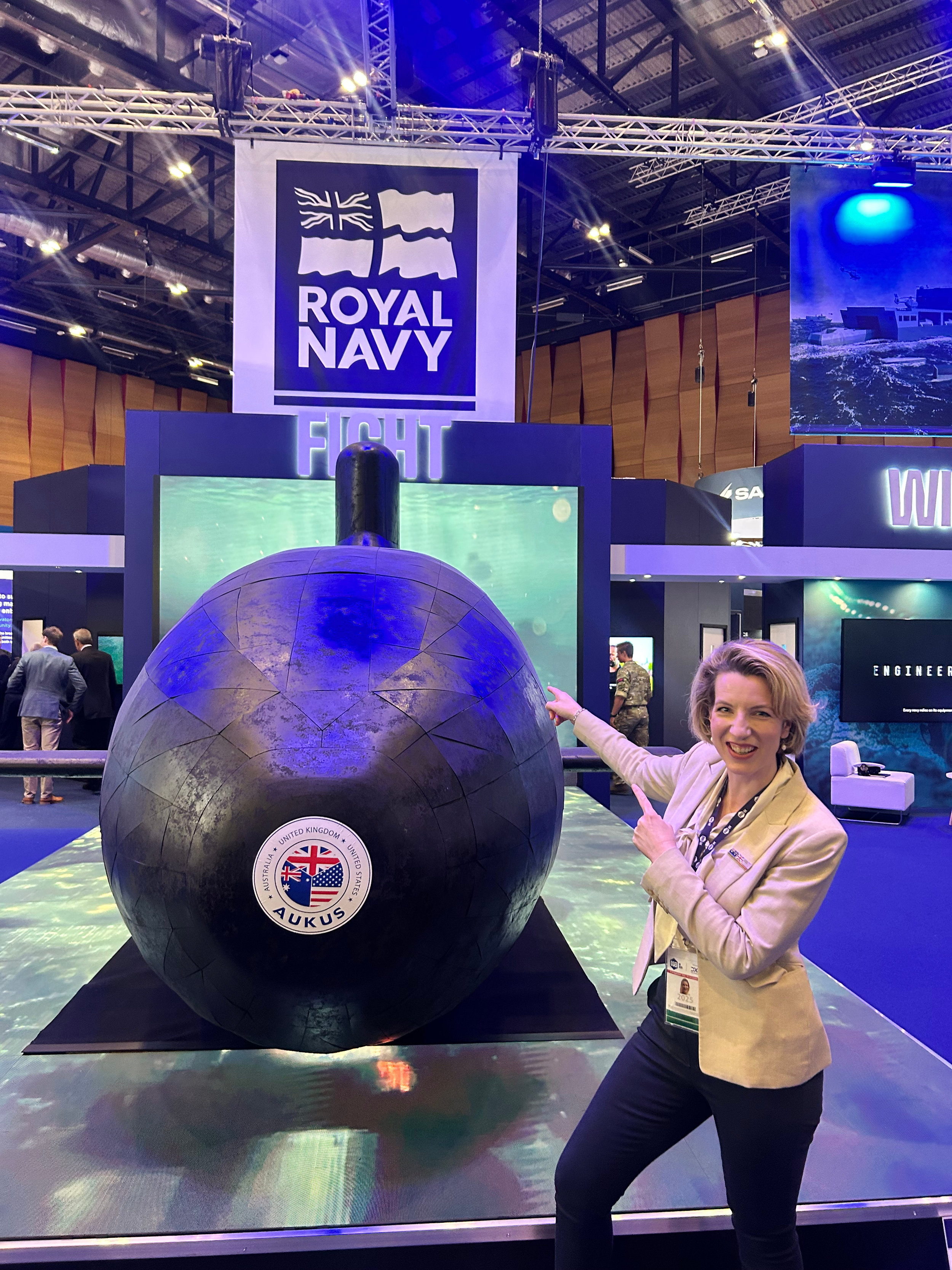 Lauren standing infront of a large submarine model at a conference