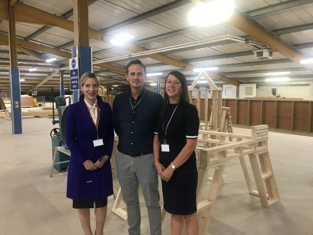 Lauren standing with two leaders in a carpentry workshop 