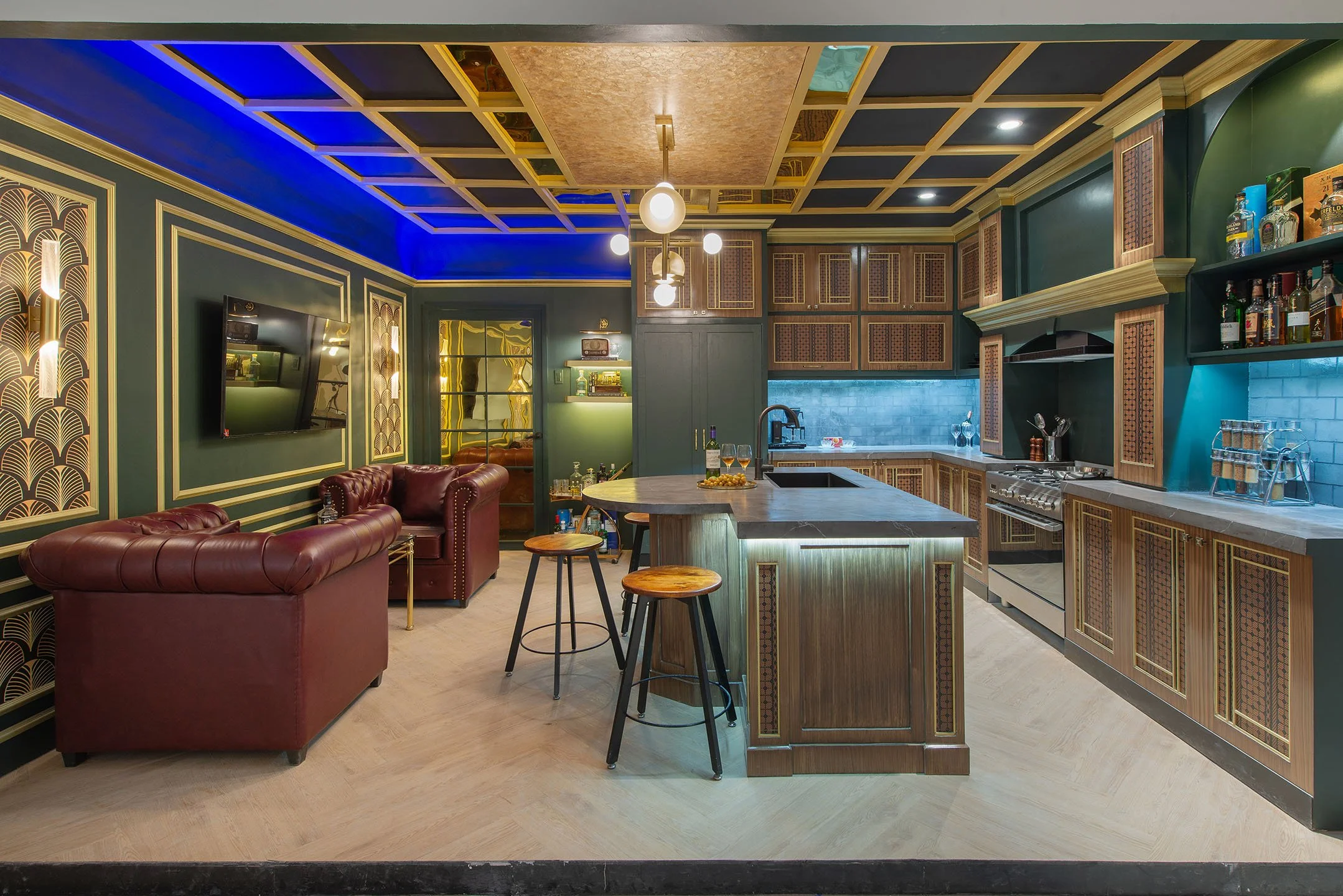 Modern living room and open kitchen with green walls, gold accents, dark wood cabinetry, and a marble kitchen island with bar stools, exposed brick backsplash, and decorative lighting.