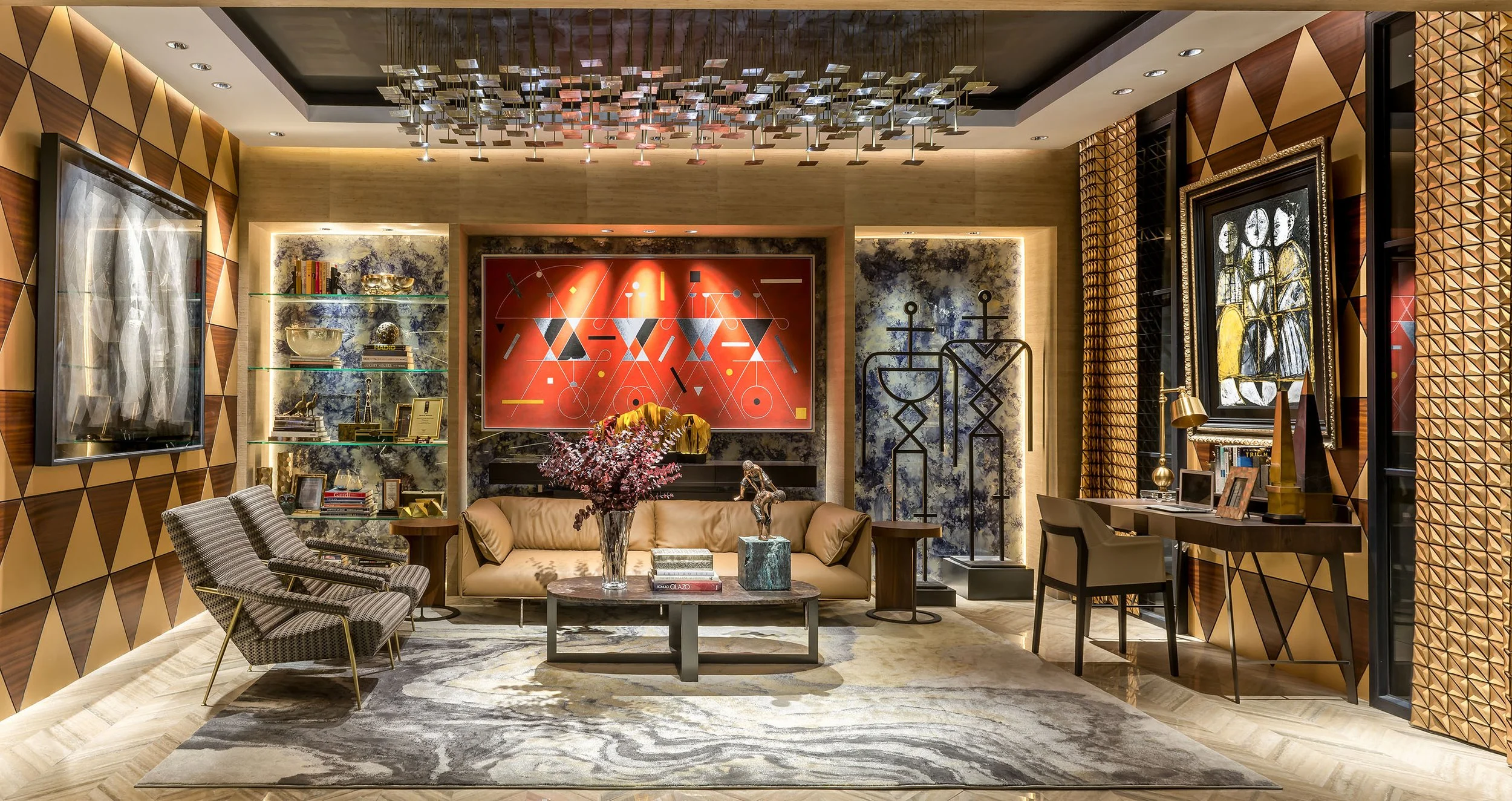 A decorated living room with patterned walls, a beige sofa, two chairs, a coffee table with books and a flower arrangement, shelves with decorative items, and abstract artwork on the walls.