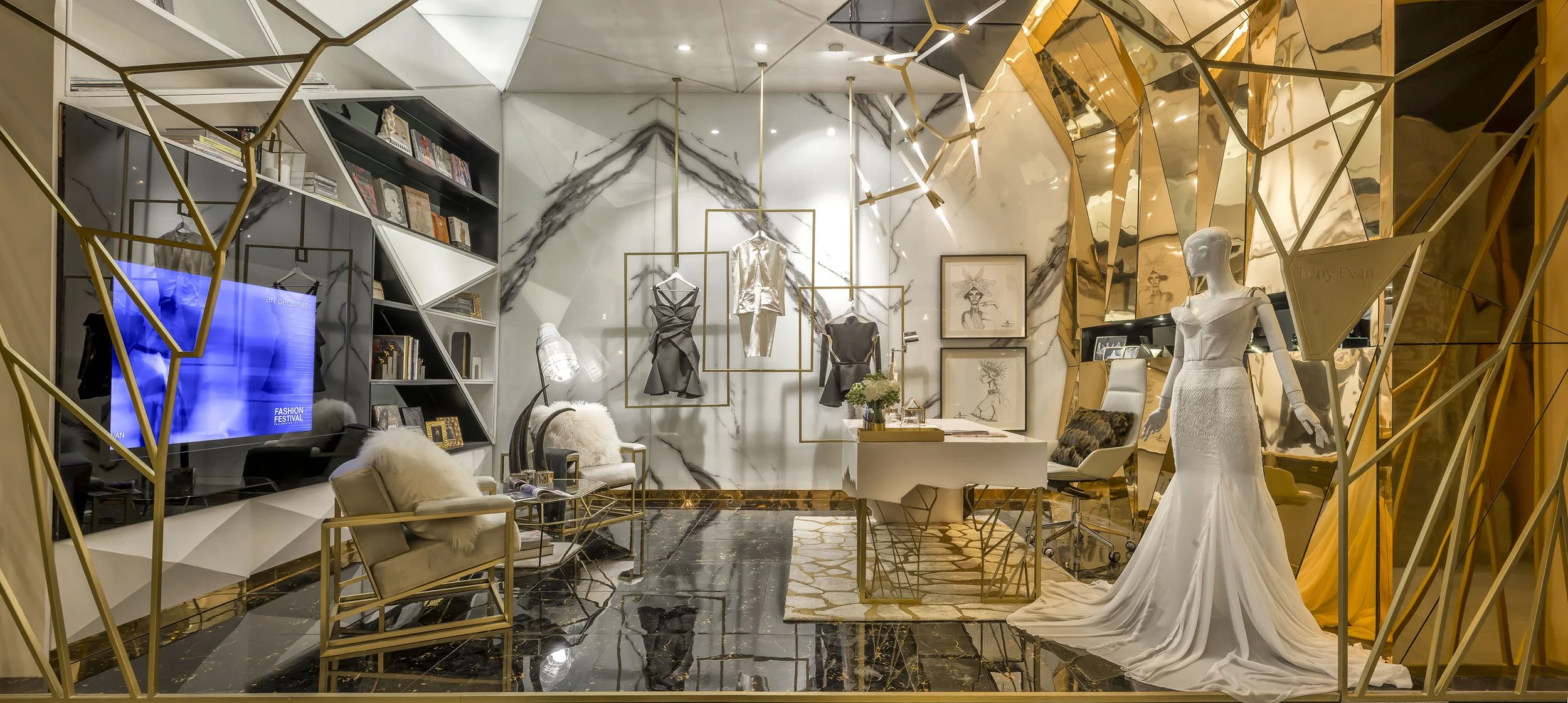 An upscale interior space with marble walls and floors, gold geometric accents, a mannequin in a white wedding gown, framed artwork, a black desk with a computer, and stylish chairs with fur accents.