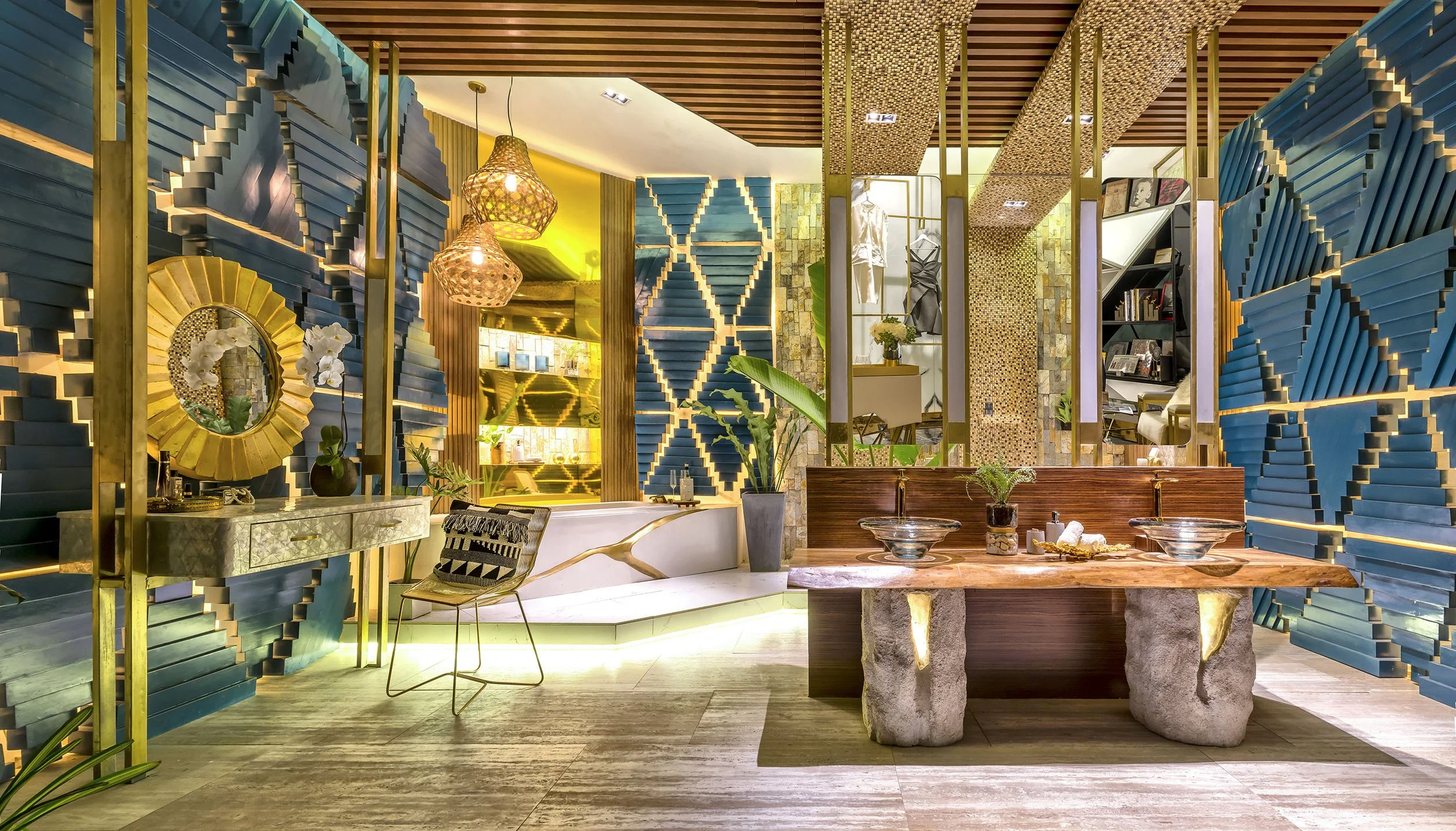 Interior of a stylish room with blue geometric patterned walls, gold accents, green plants, a marble-topped table, and decorative lighting and artwork.