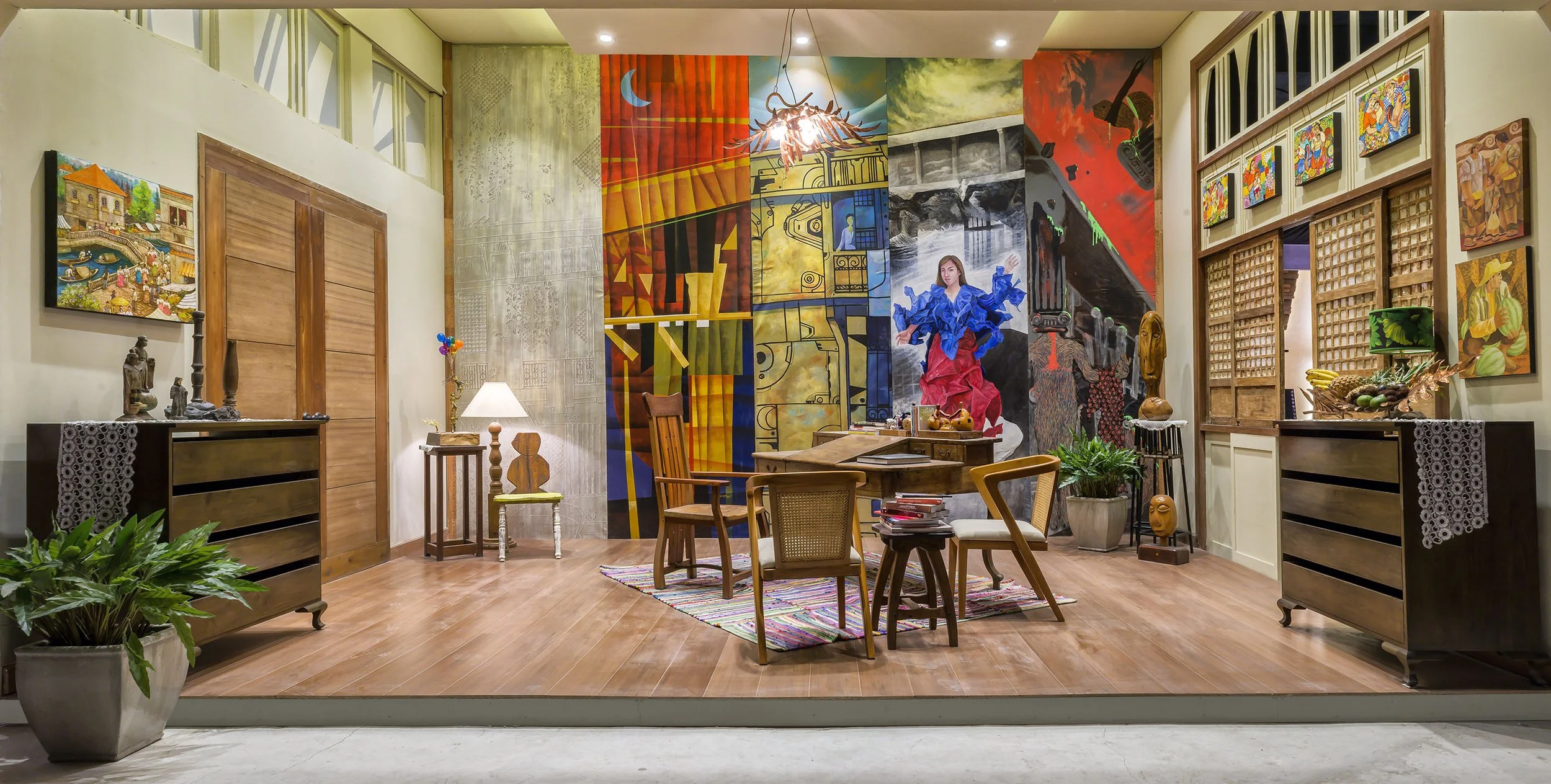 Interior of an art gallery with colorful paintings and sculptures, wooden furniture, and potted plants.