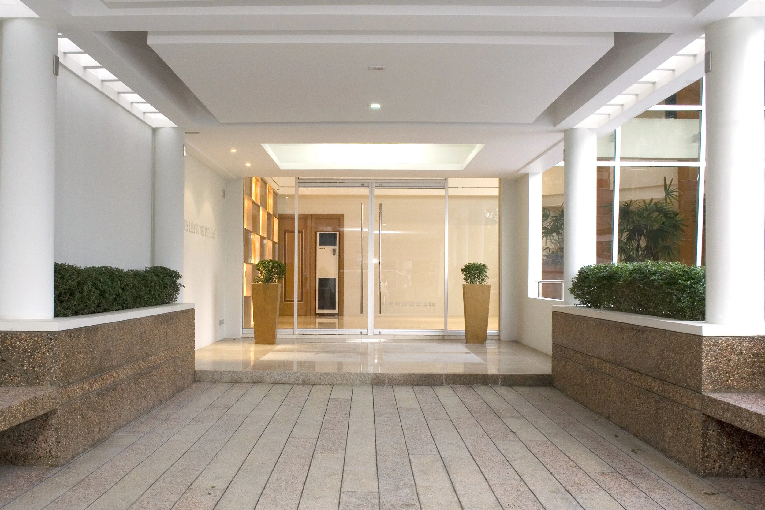 Lobby area with glass doors, potted plants, and modern design elements in a building.