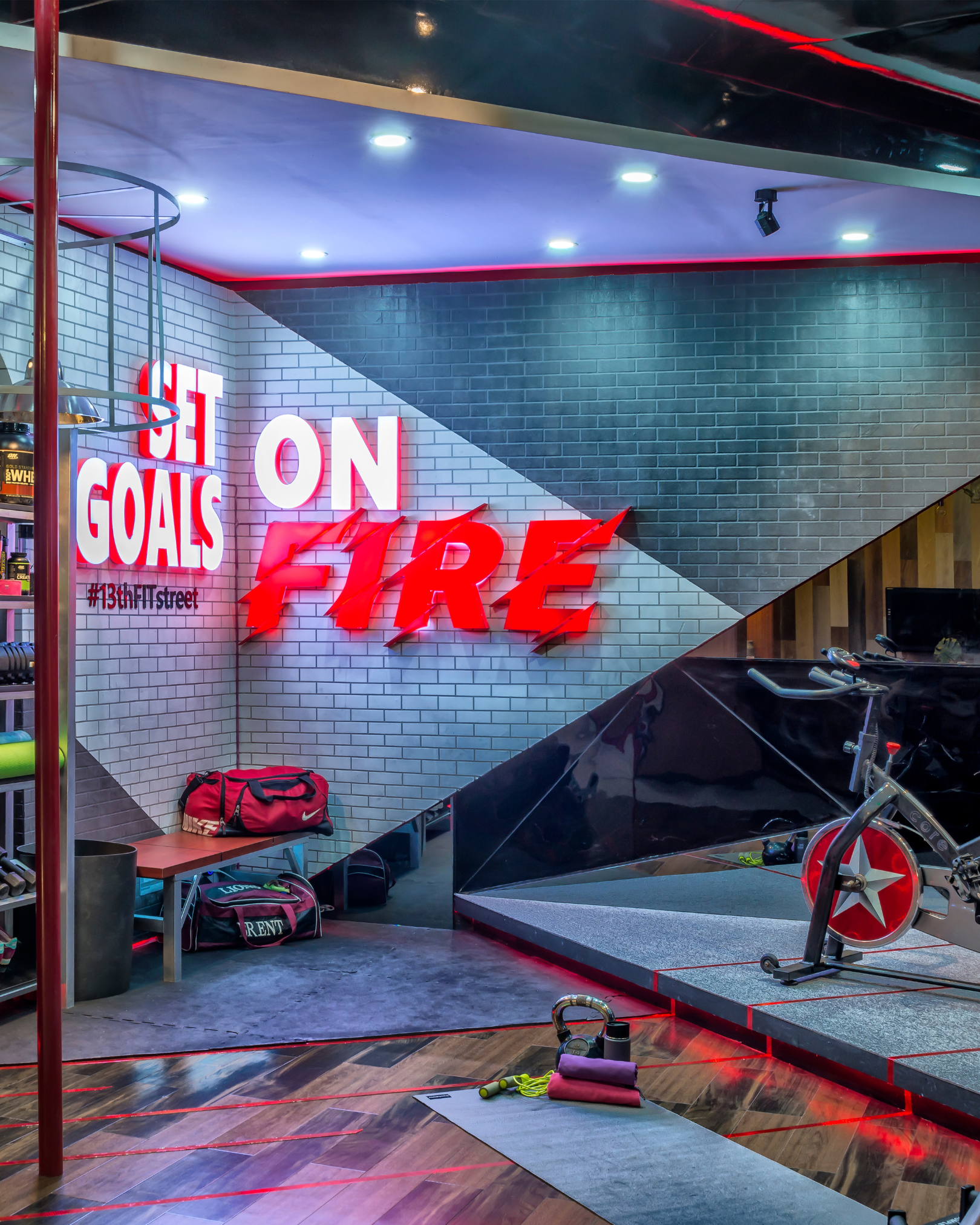 Indoor fitness area with exercise equipment, a punching bag, and fitness accessories, illuminated by ceiling lights and red LED accent lighting.