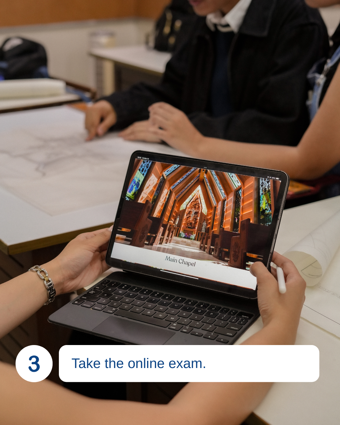 Person taking an online exam on a tablet, with a church interior displayed on the screen labeled 'Main Chapel'; other students are seated at desks in the background.