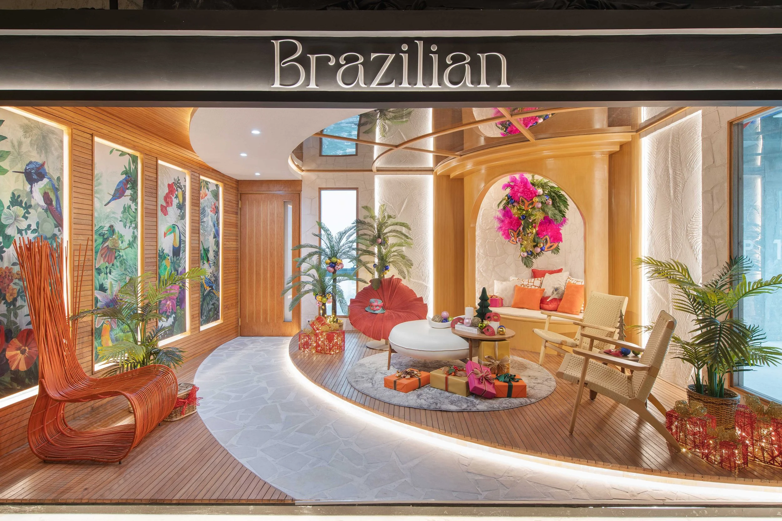 Decorated space with tropical theme, featuring vibrant bird and floral artwork, holiday decorations including wrapped presents, and a cozy seating area with orange, pink, and beige cushions.